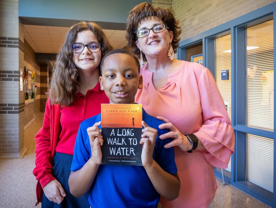 Two students and a teacher posing and smiling for photo