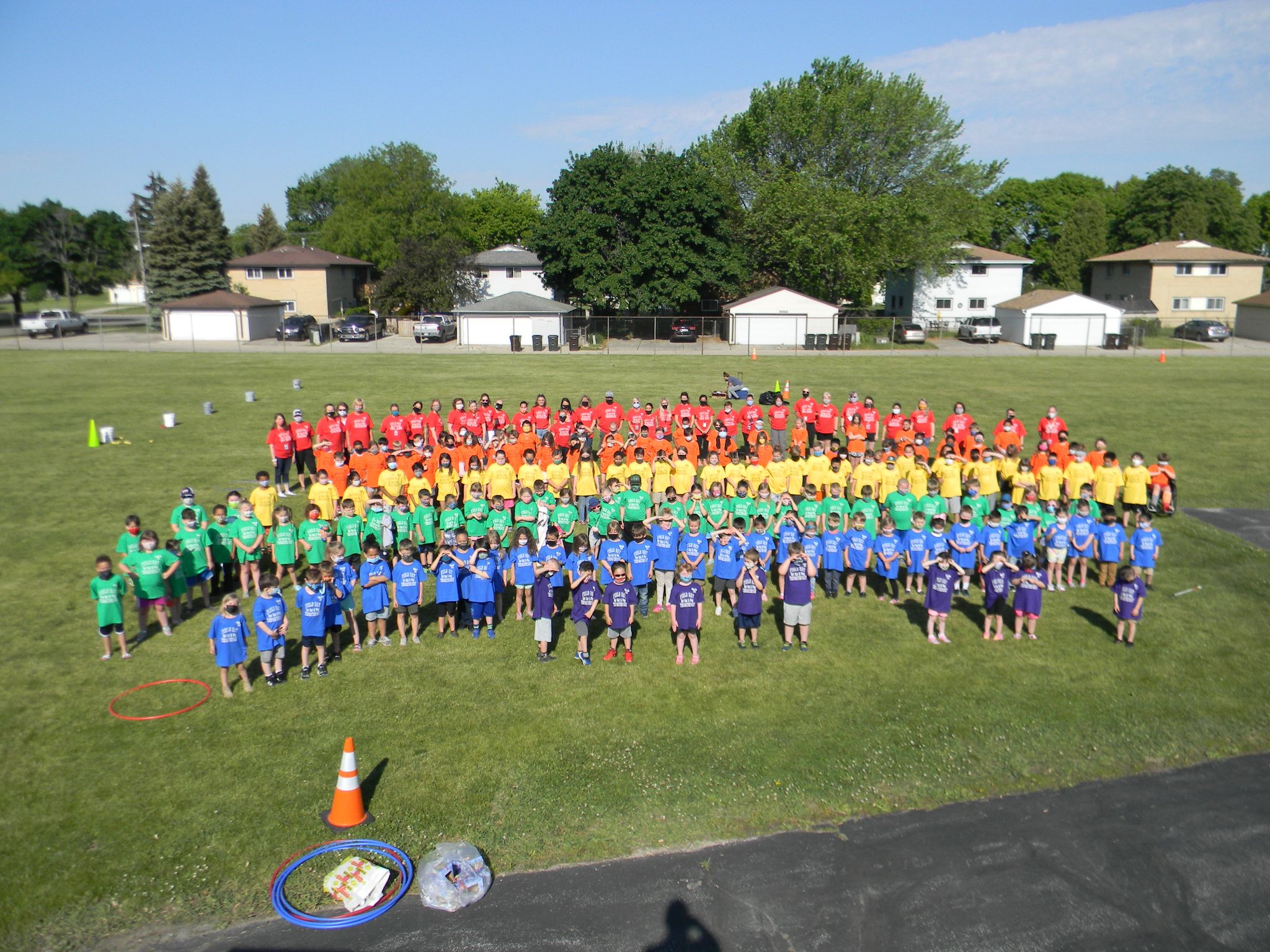 Students posing in colored shirts in the middle of a field Aerial view of field day in 2021