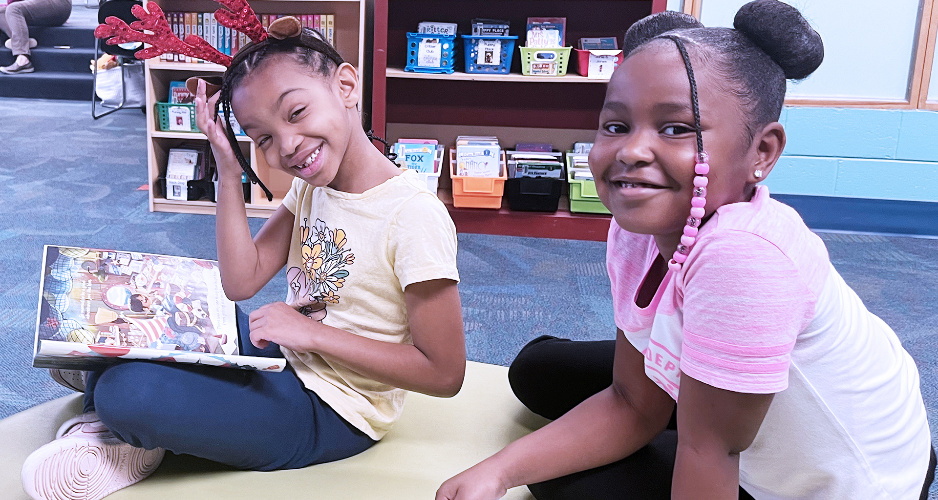 Two students in library smile for a photo.