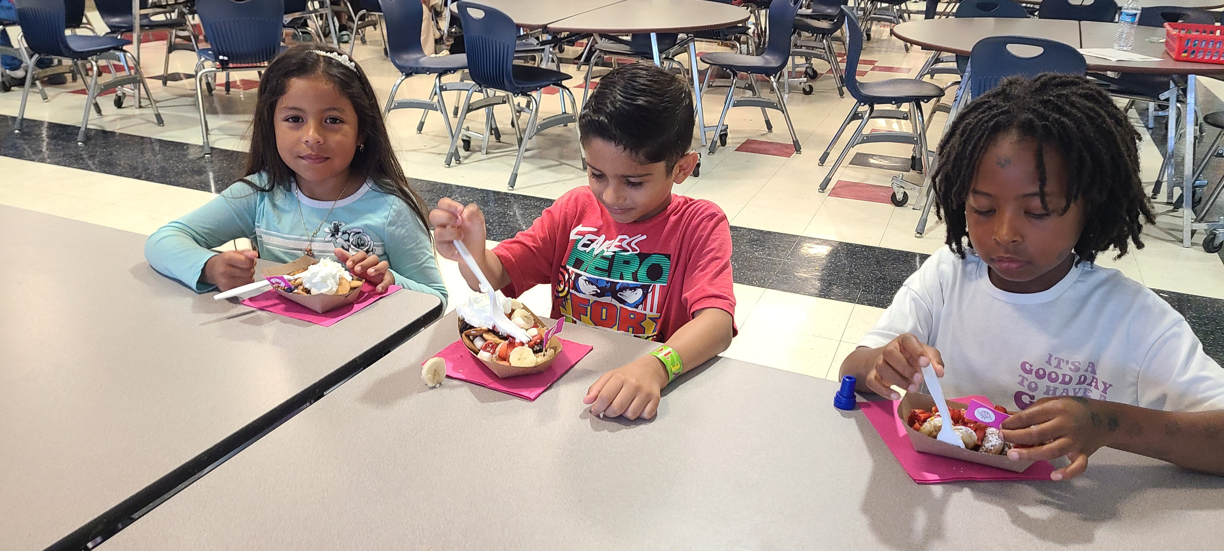Three students sitting at the lunch table with their lunchbox