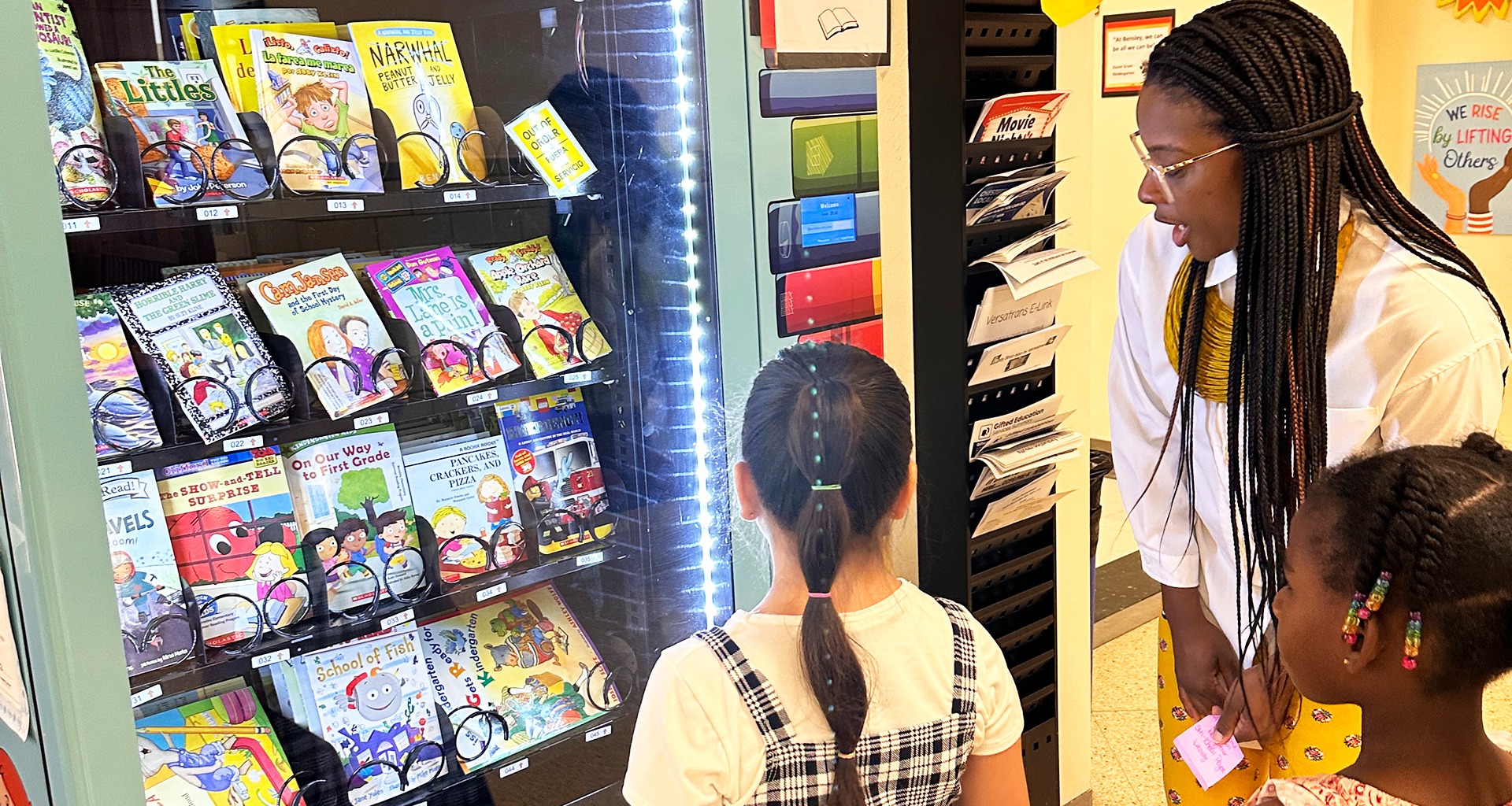 teacher helping students pick books from a vending machine.