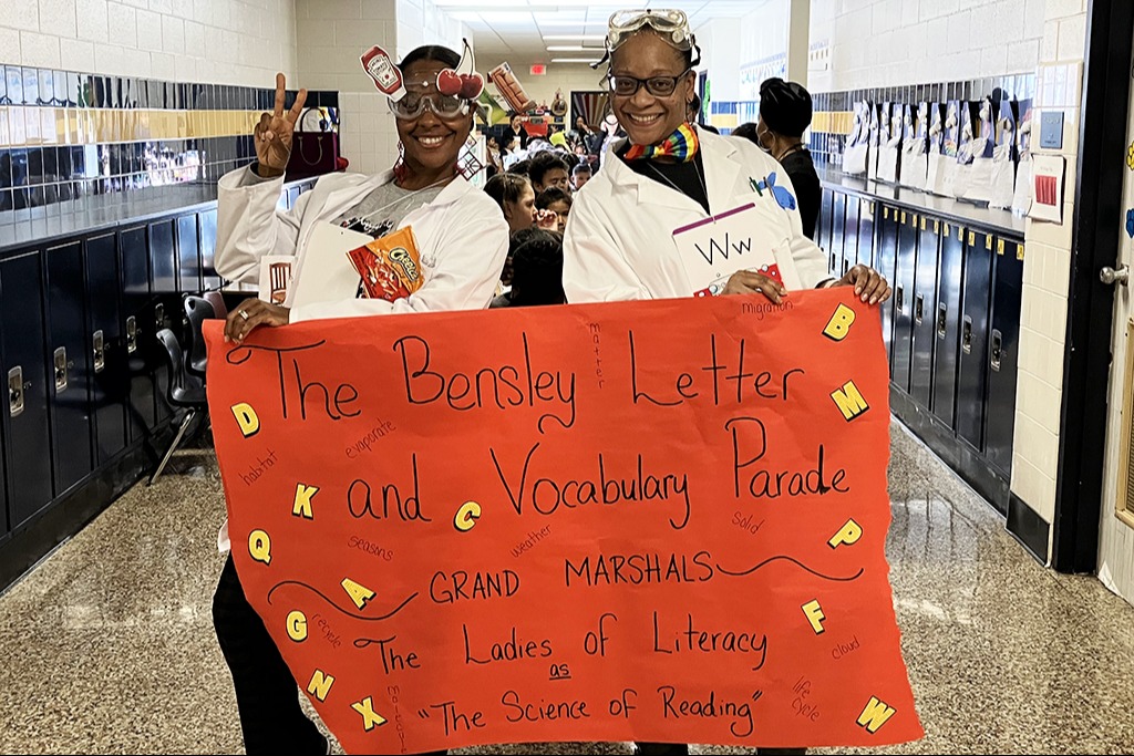 Teachers hold up a sign about their parade.
