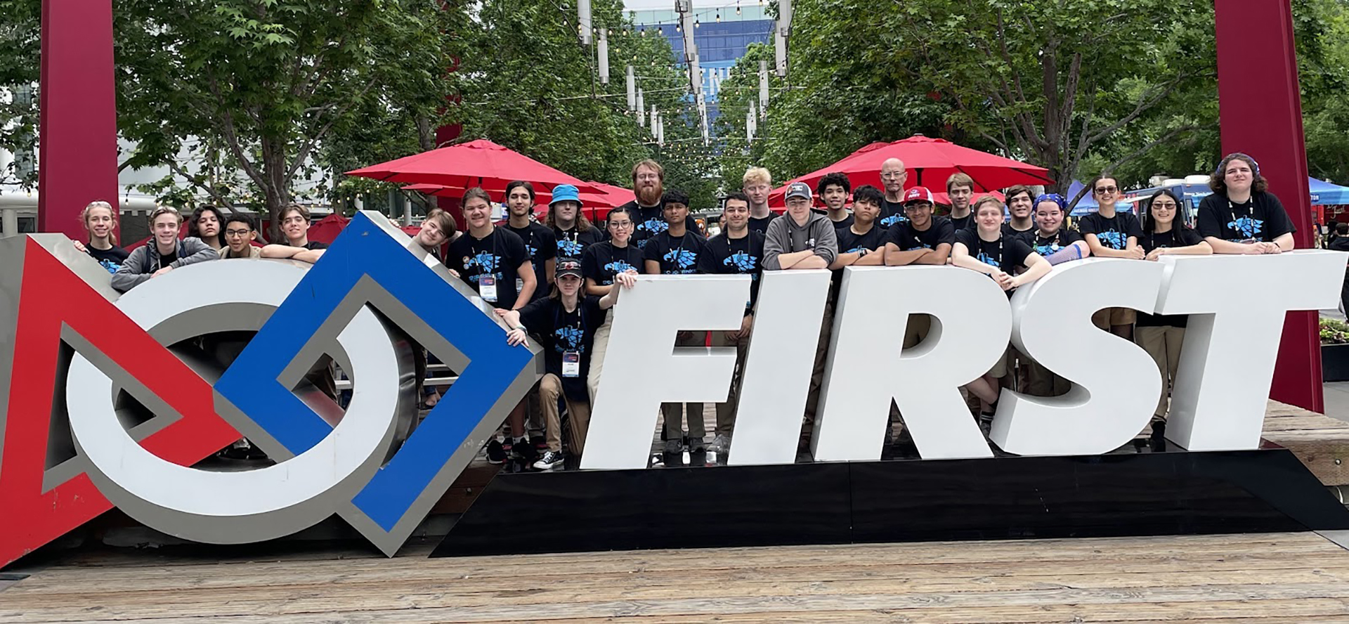 large group poses in front of first sign