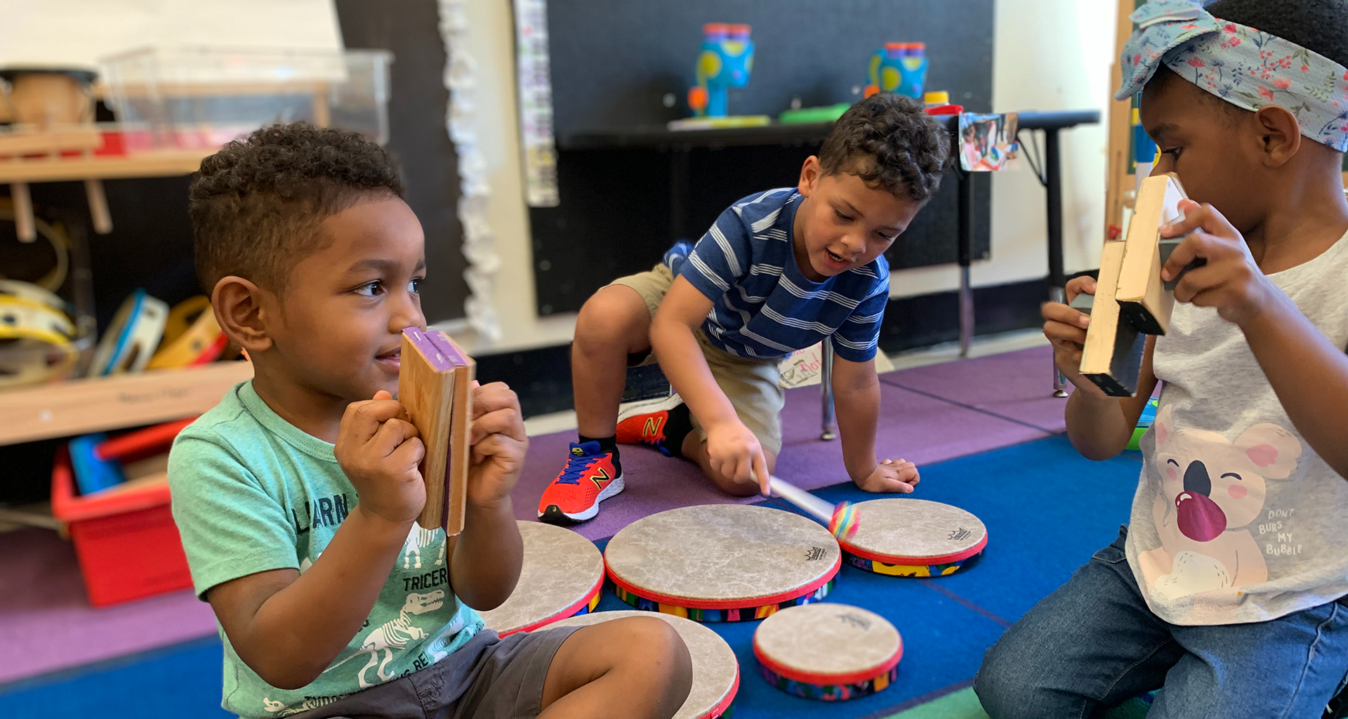 Three students playing with instruments in the classroom