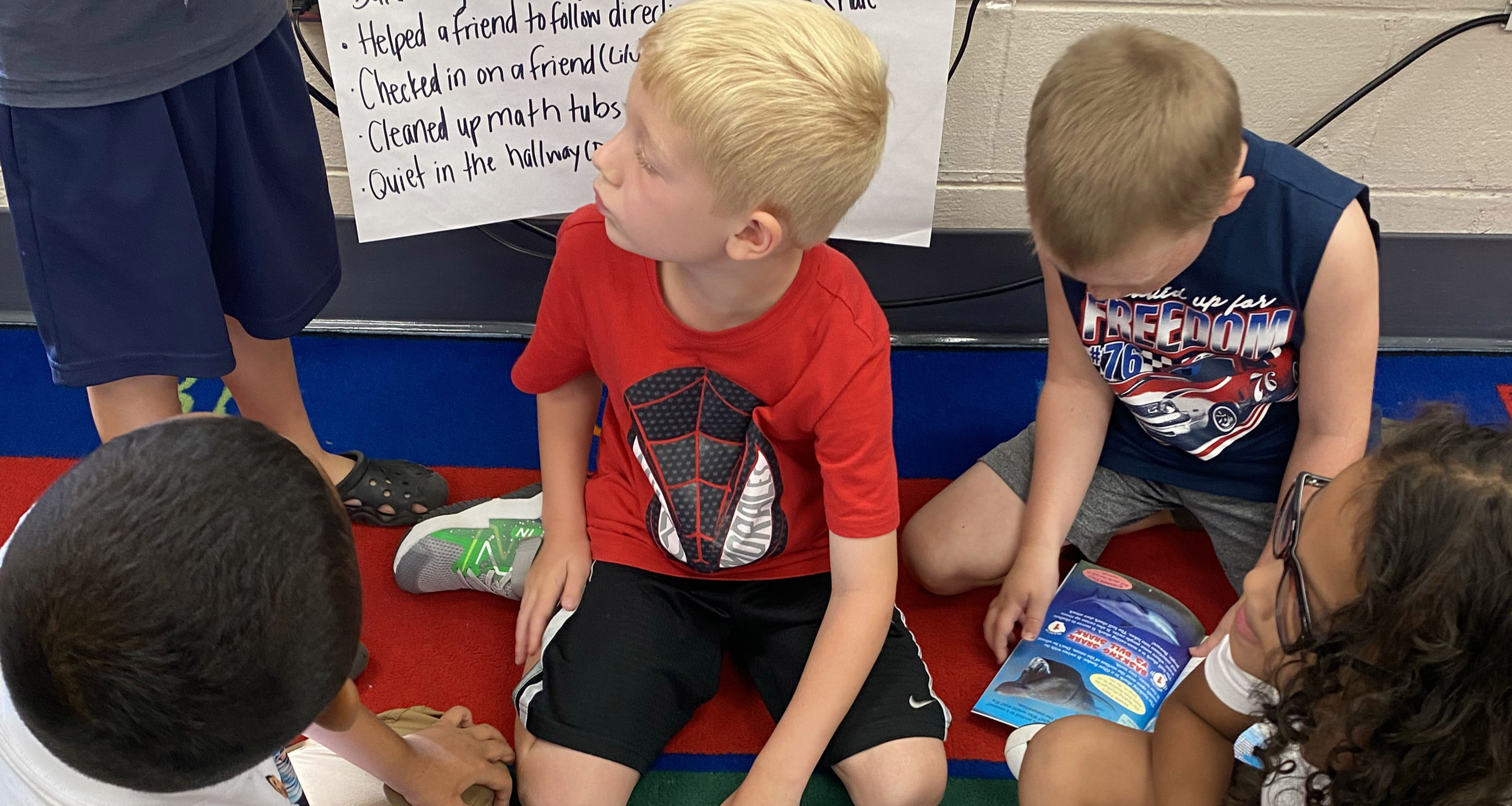 A group of students reading books on the carpet