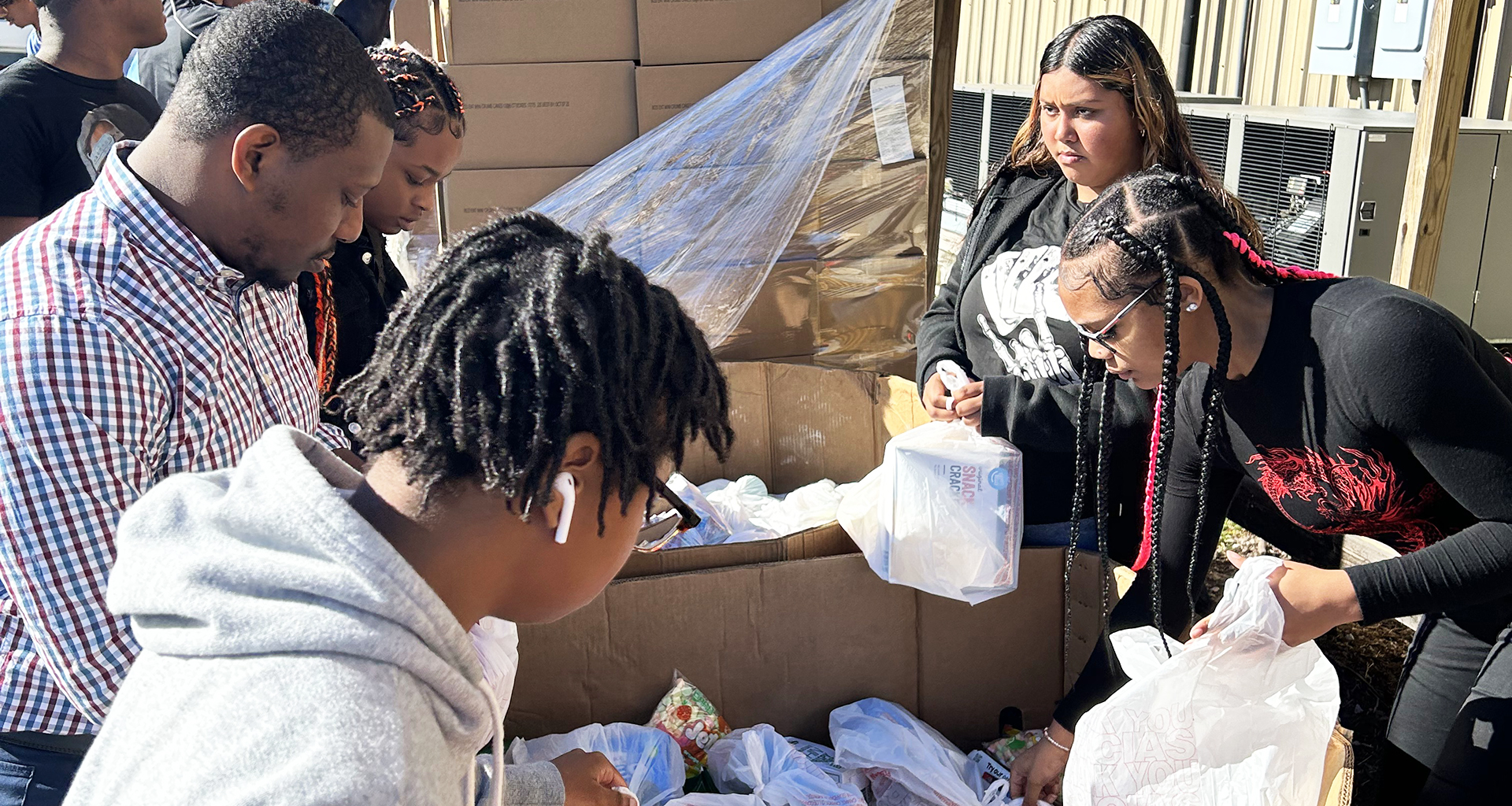 Large group of students pack bags at food bank
