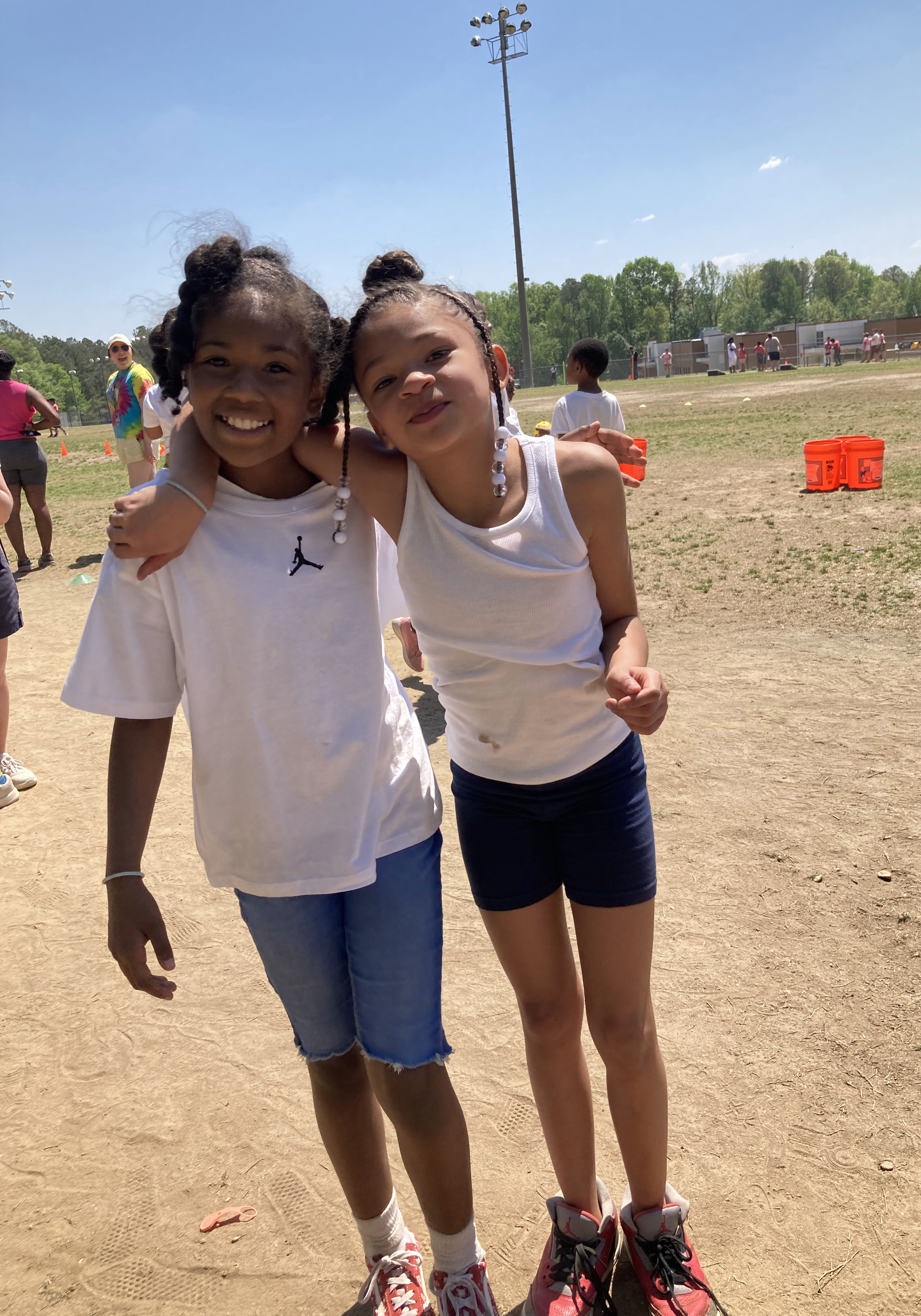 Two girls outside hug and pose for camera