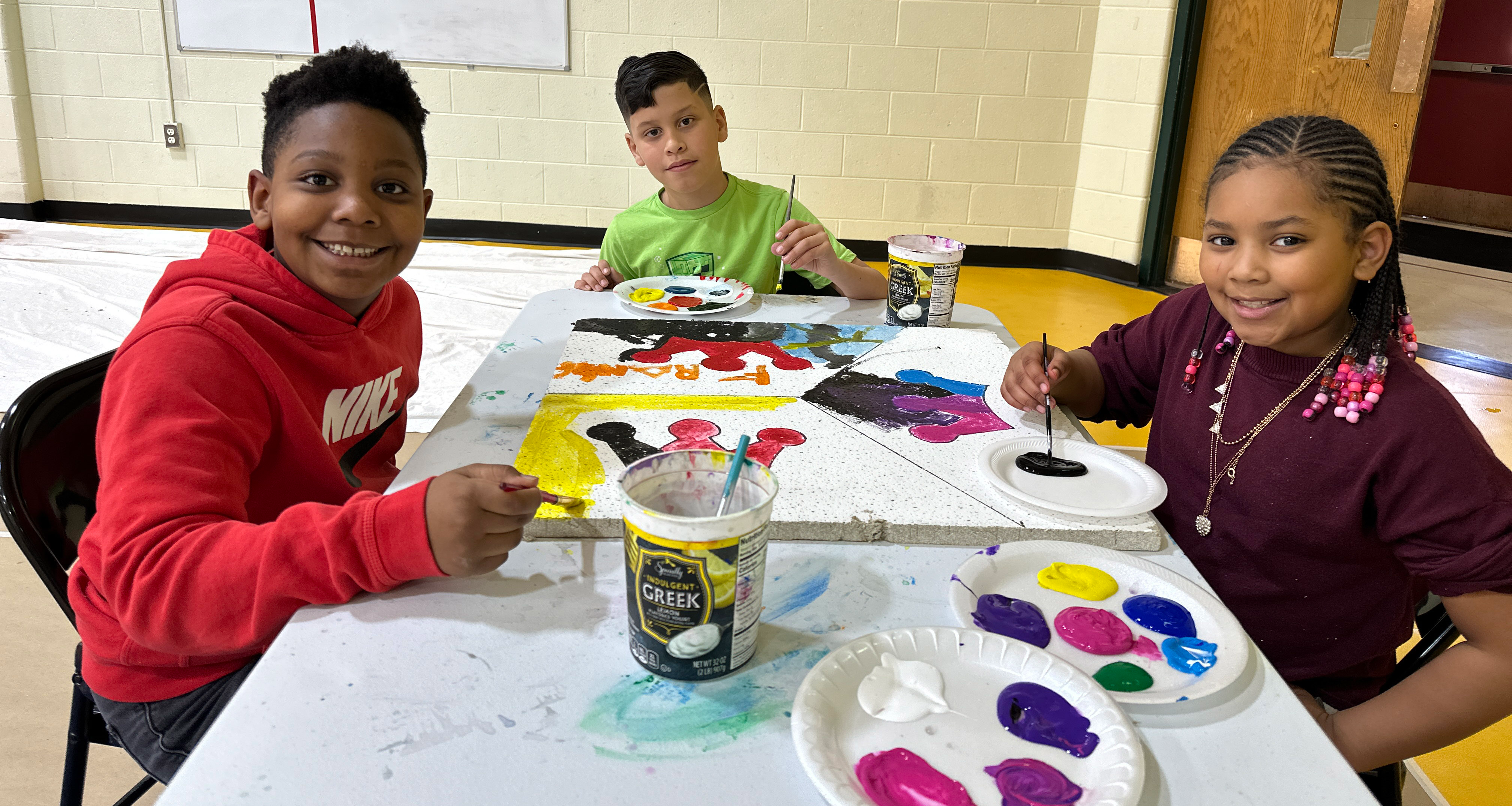 Three students painting a ceiling tile