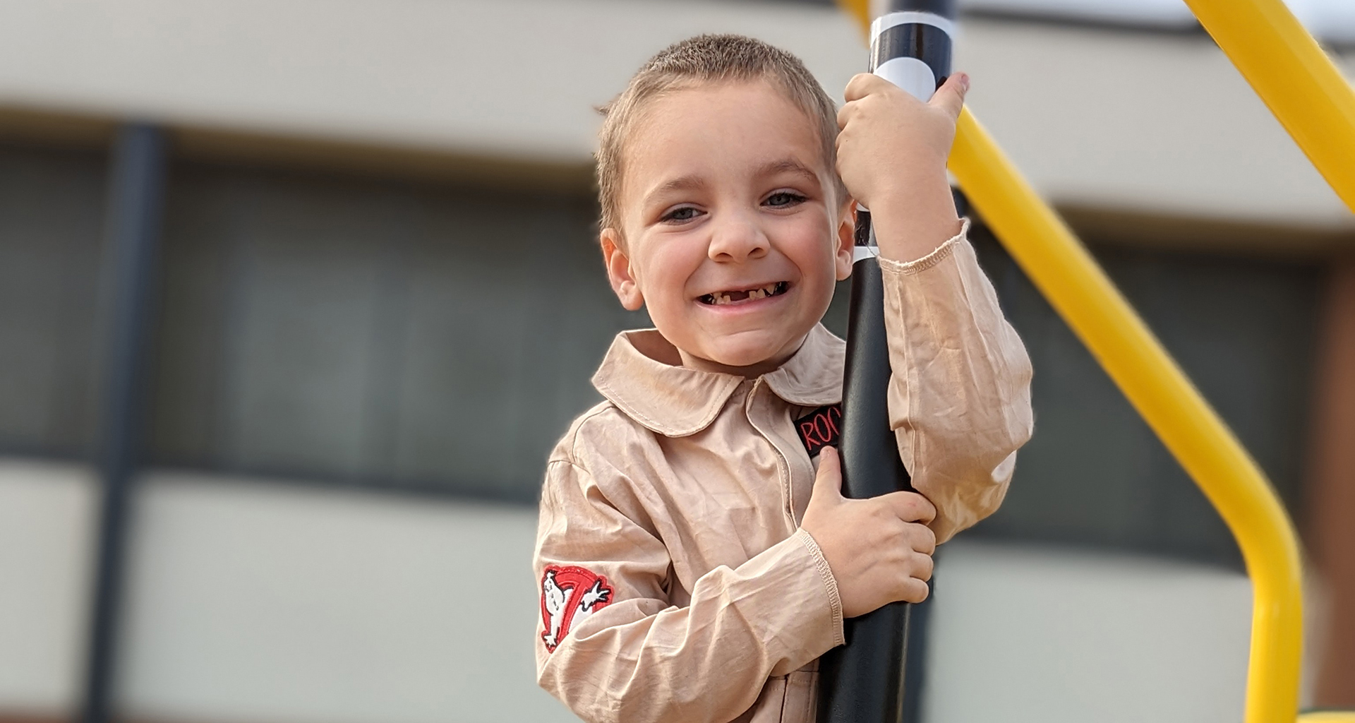 Male student on playground equipment smiles for the camera.