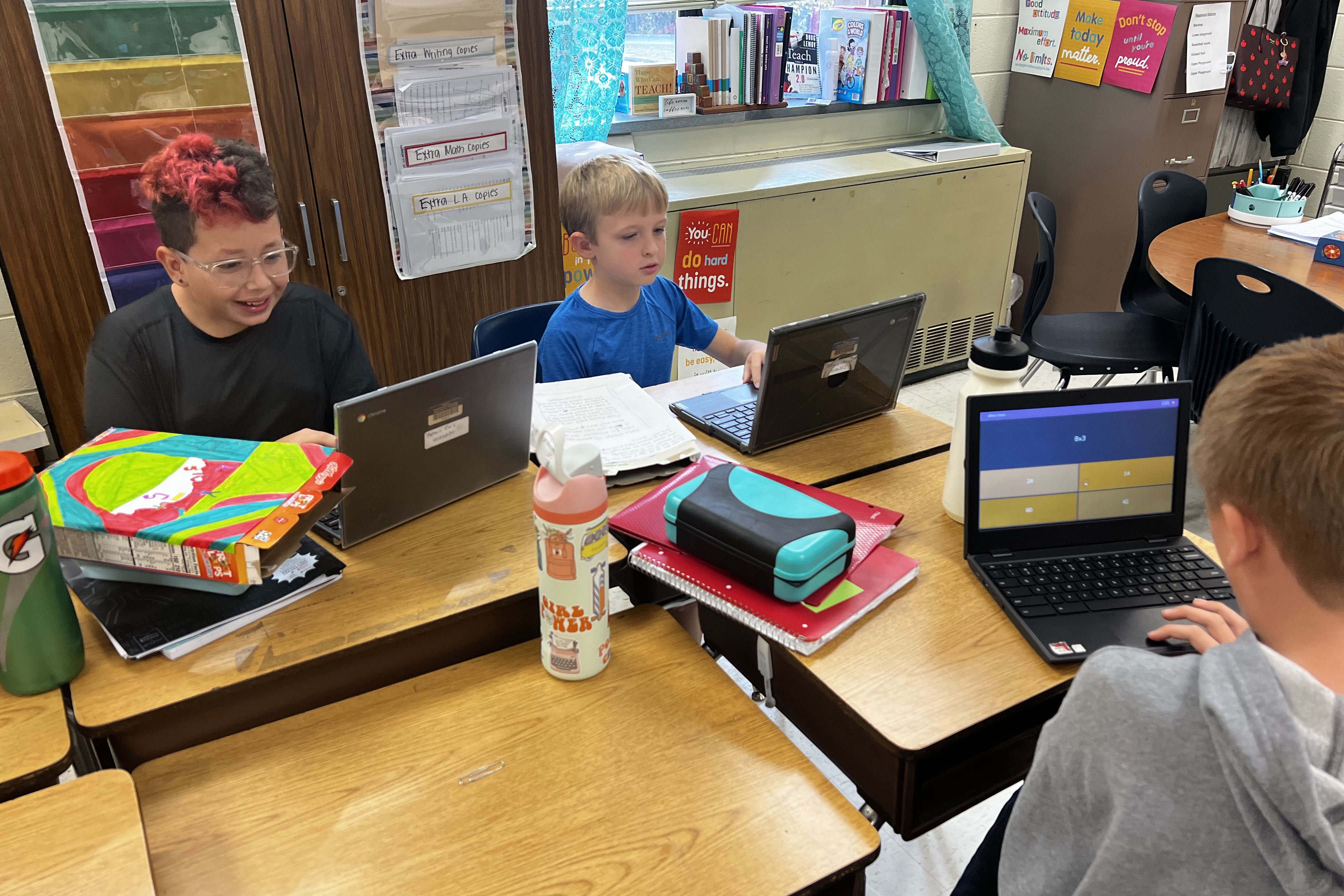 Three students working on their laptops in class