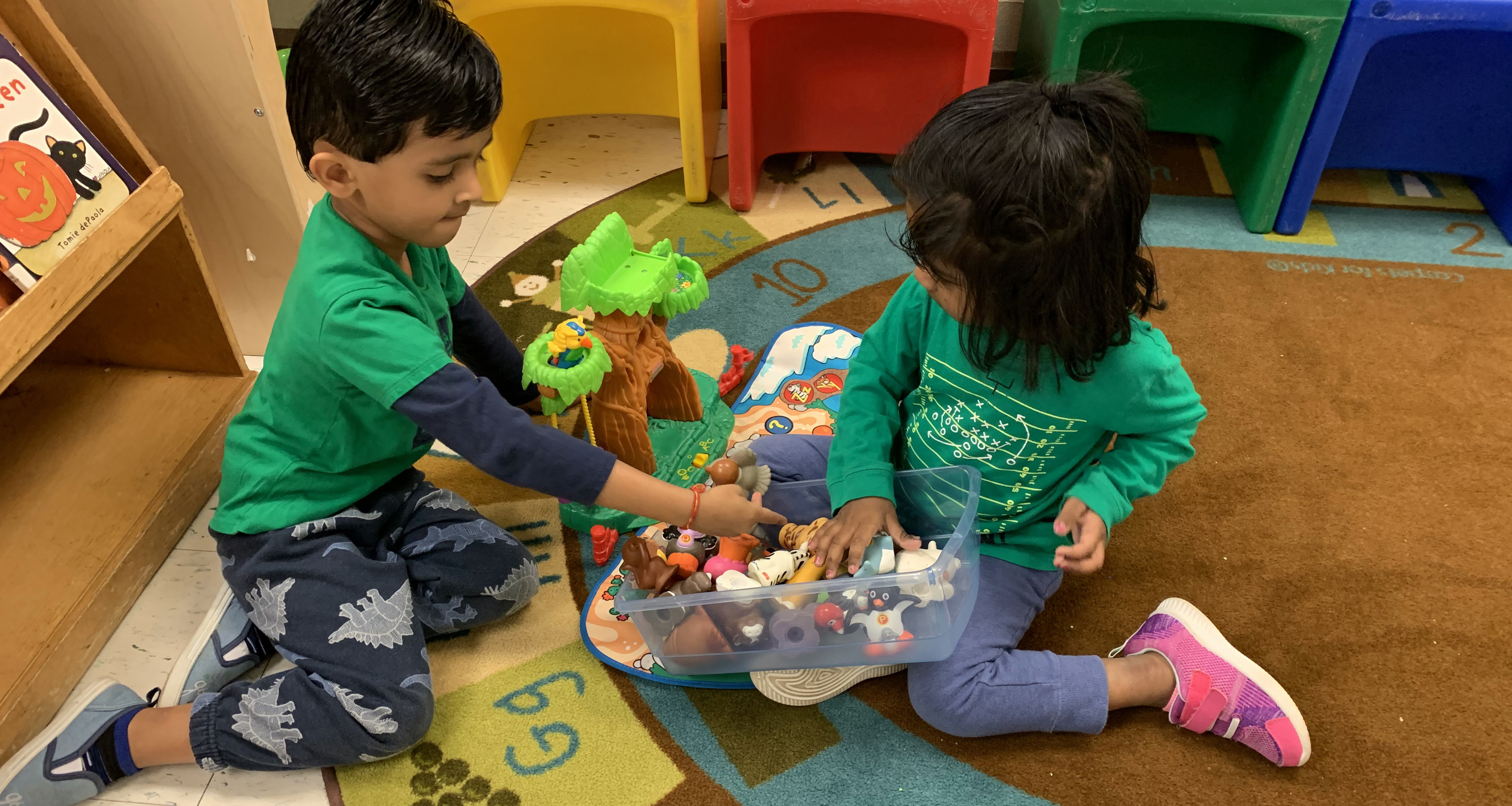Two students playing with a variety of plastic toys