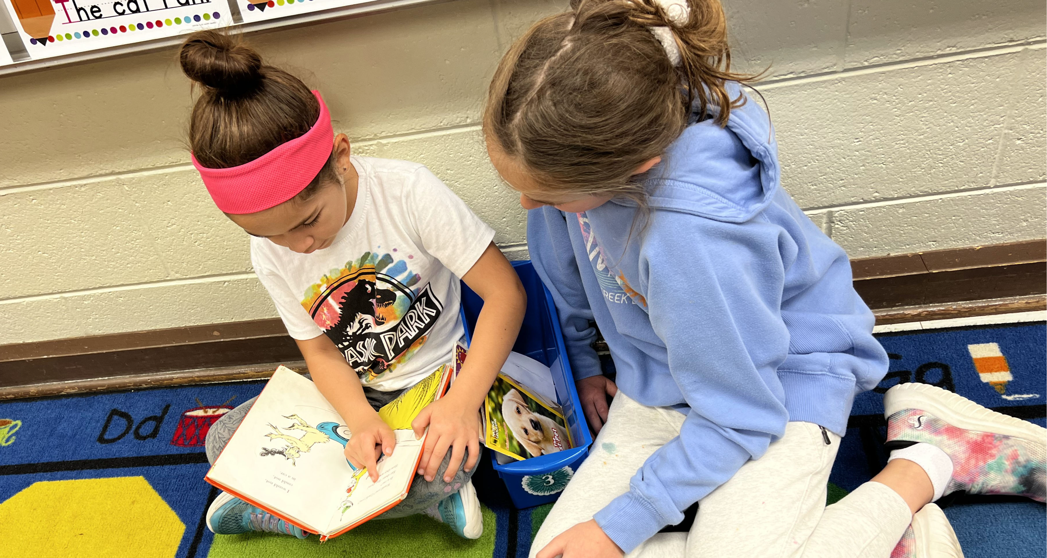 Two students reading a book together in class