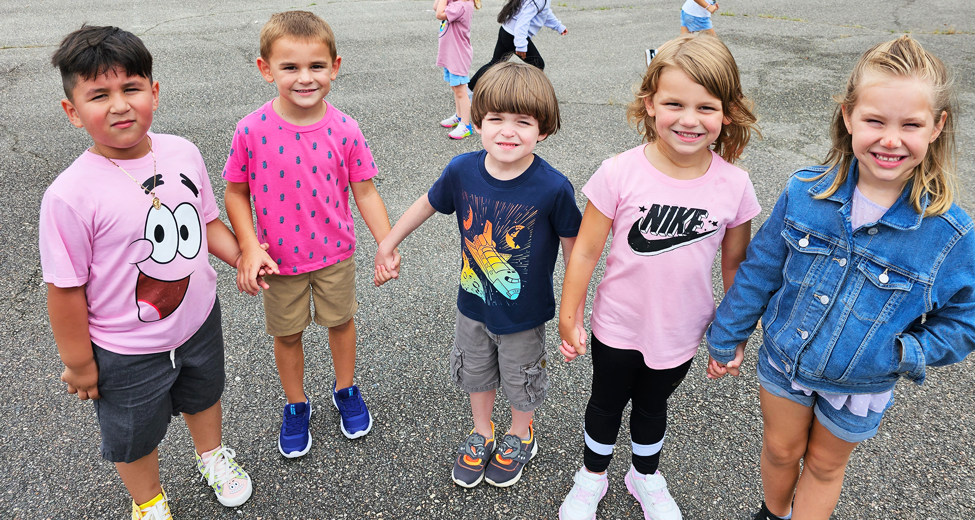 Five student s hold hands on the playground.
