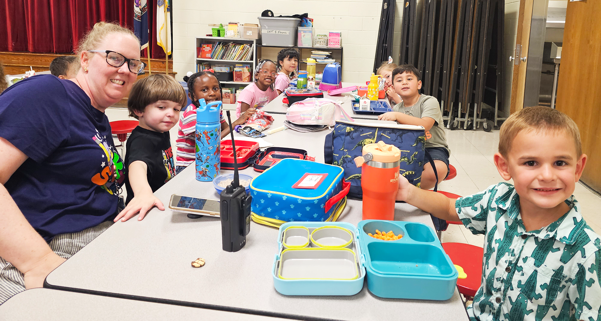 students sitting at the lunch table with food in a lunchbox