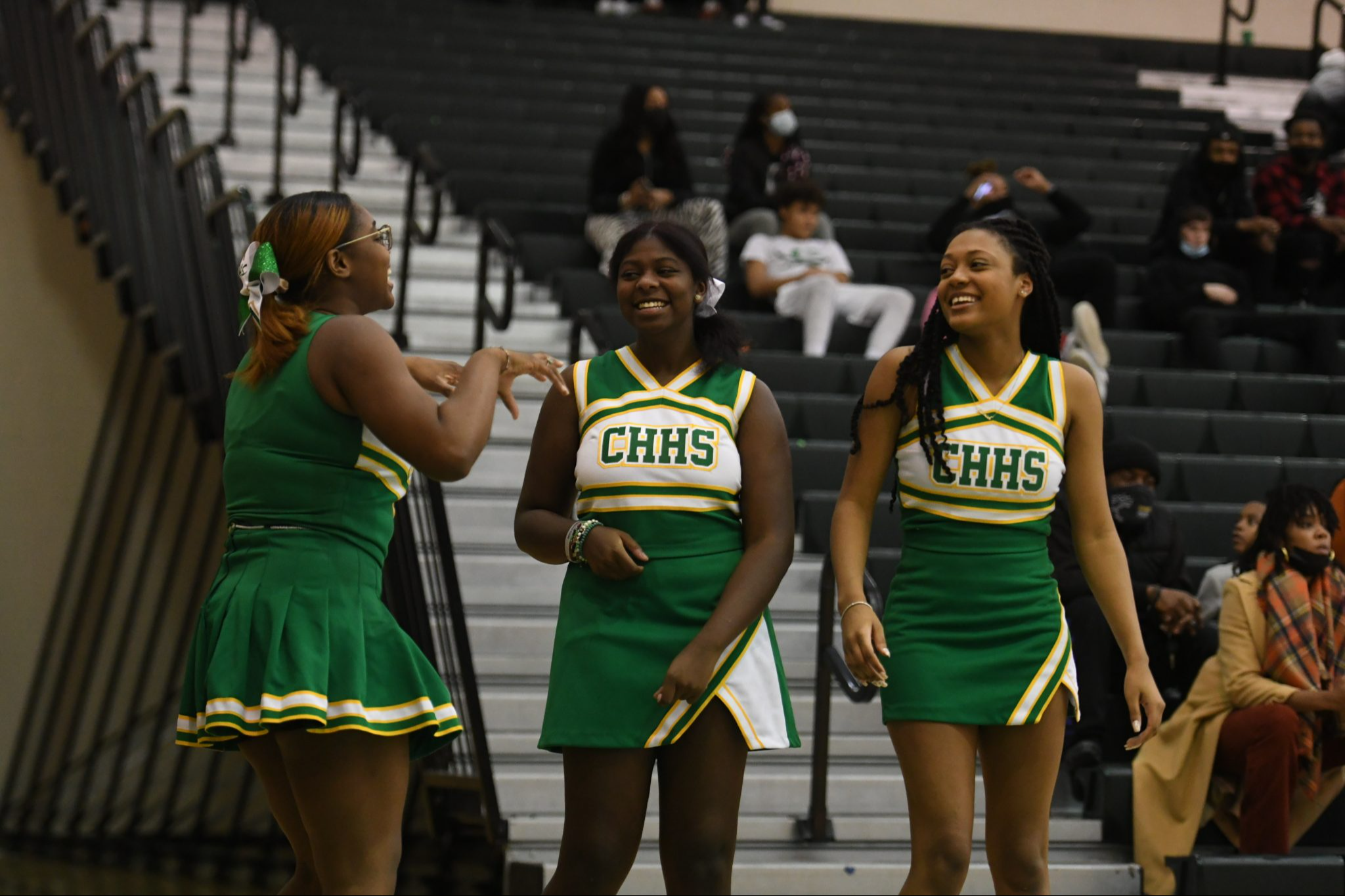 Three cheerleaders laughing during a basketball game