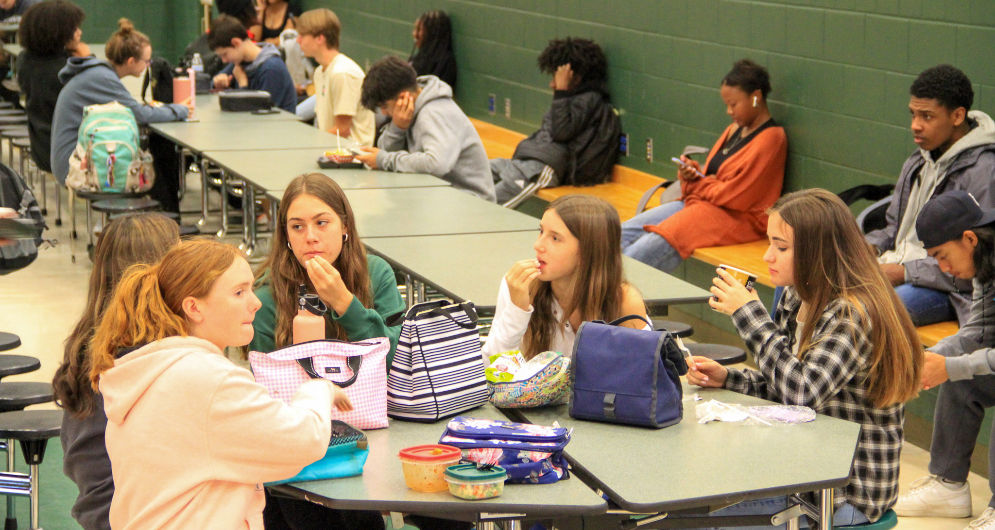 Students sitting down in the school cafeteria and eating their lunch