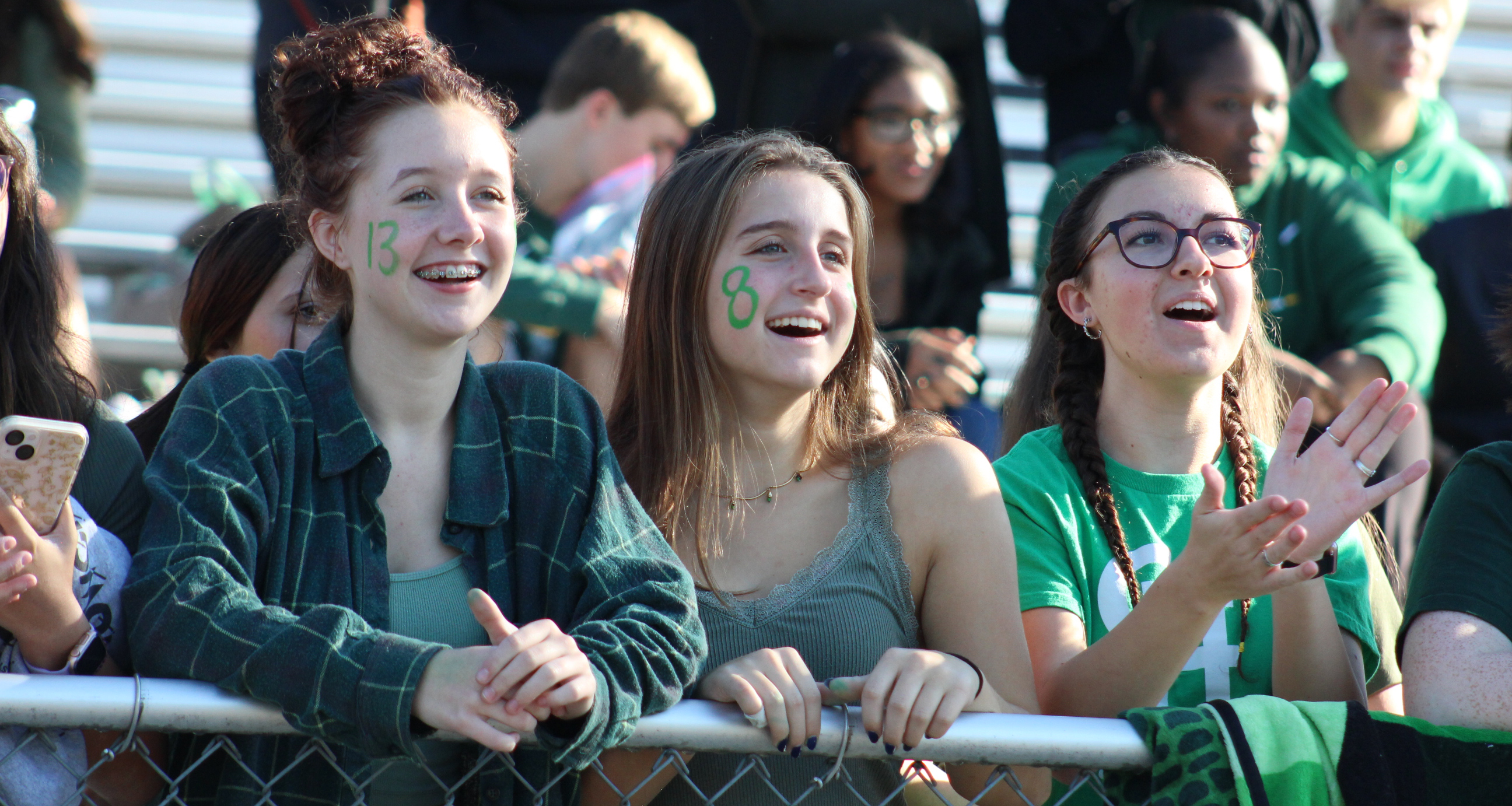 Three girls cheering from the stadium bleachers