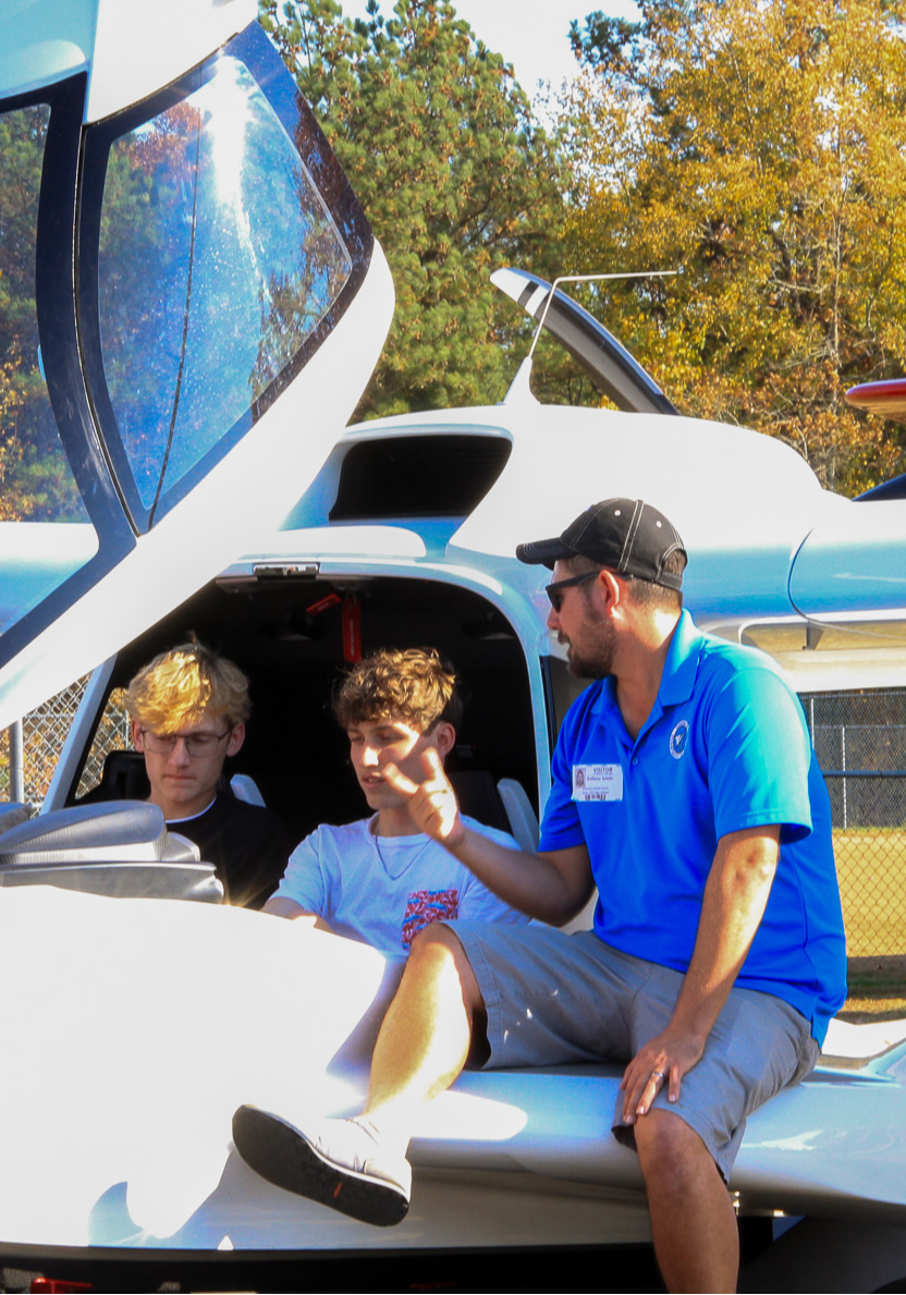 Two students in an airplane learning from an instructor about the inside of it
