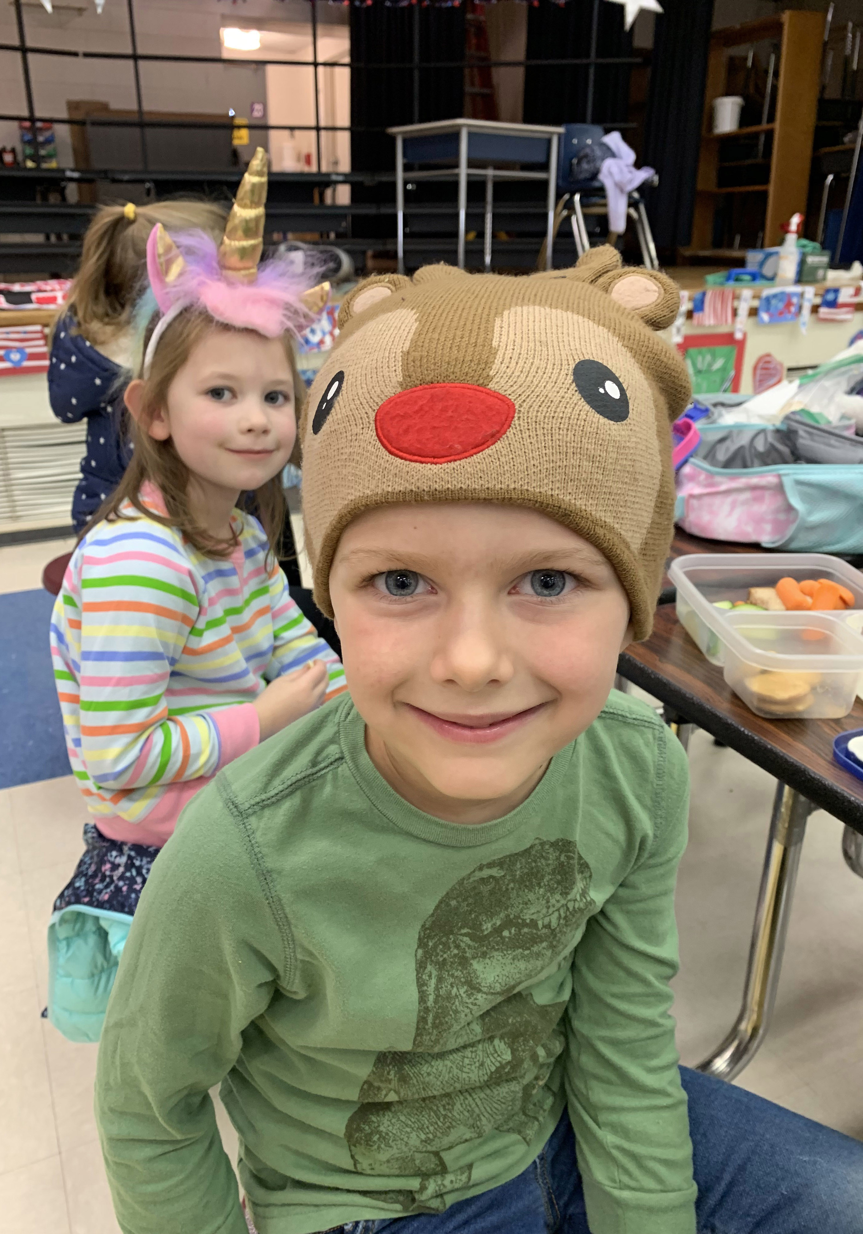 Male student wearing reindeer hat. Girl wearing unicorn hat.
