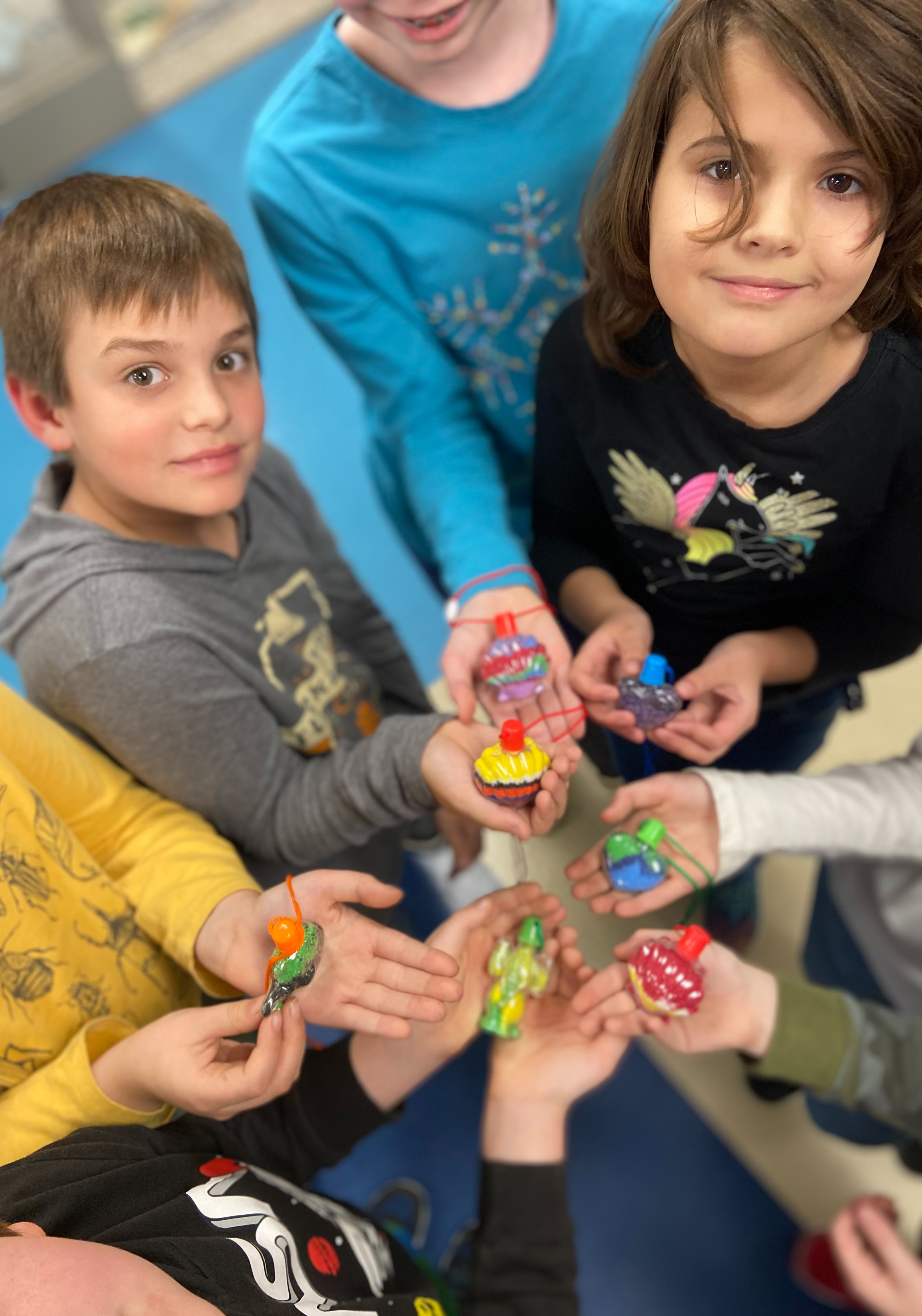 Students in a circle holding their clay projects up for the camera.