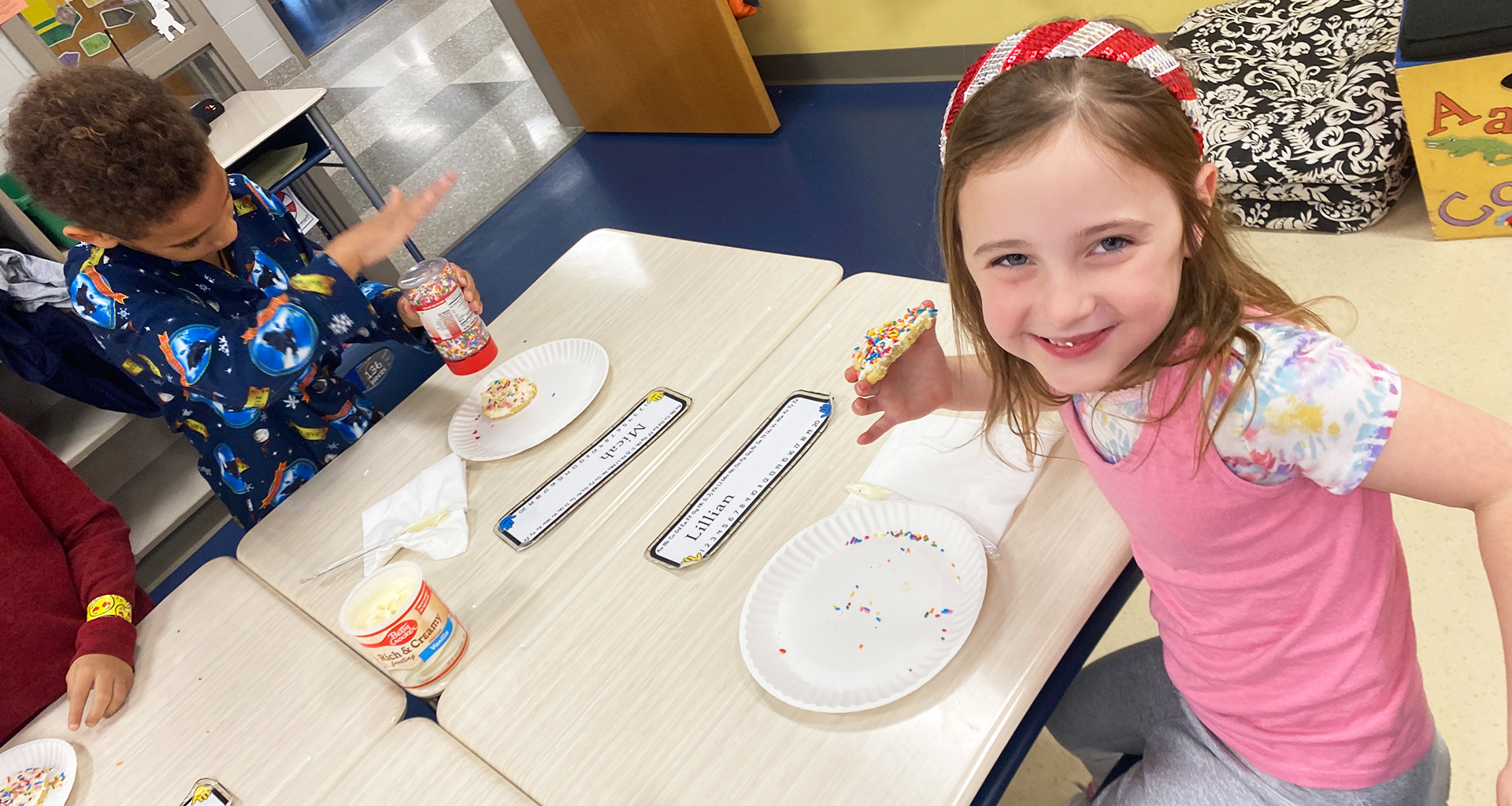 Two students adding sprinkles to cookies.