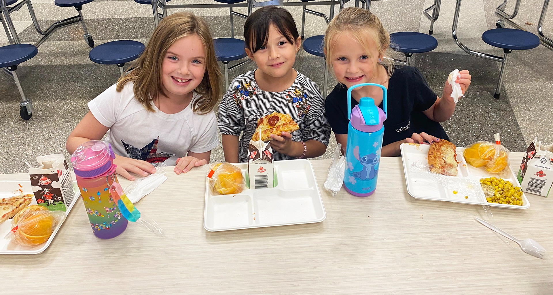 three students adding sprinkles to cookies.