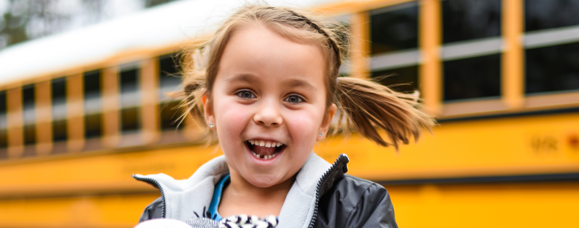 child smiling in front of bus 