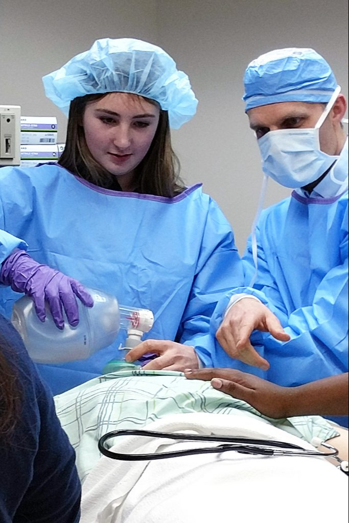 A teacher and a student working on a mannequin in a science class