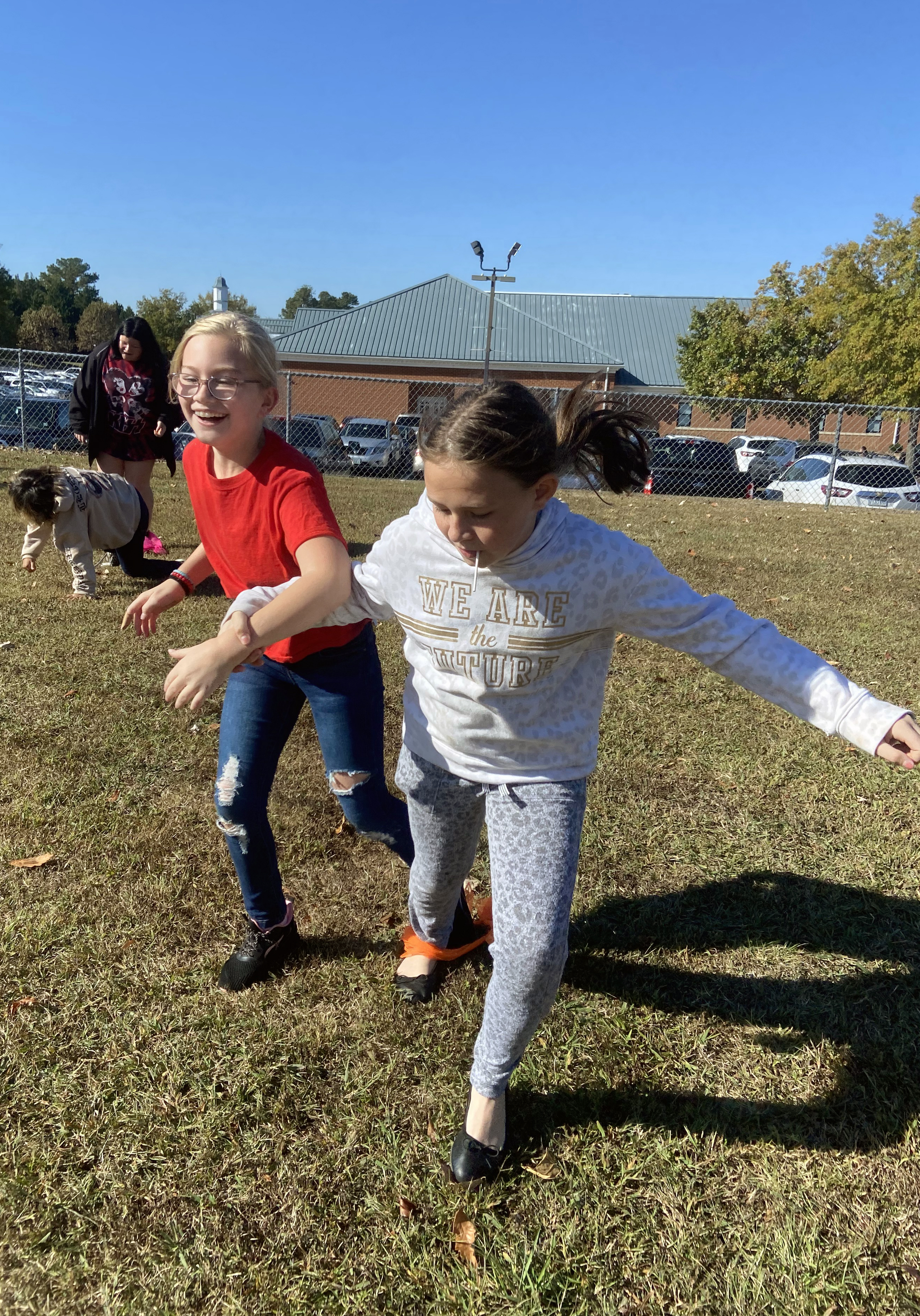 Two female students linked together running a foot race.