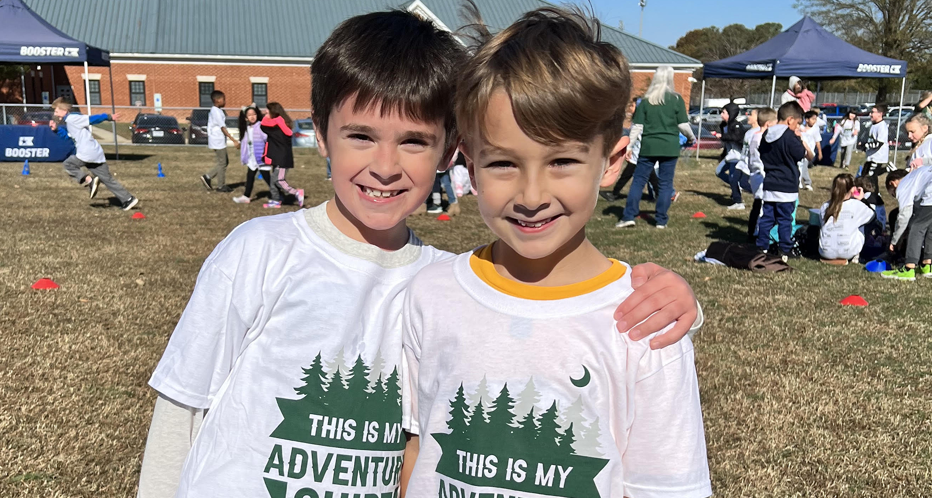 Two male students pose for a photo outside during field day.