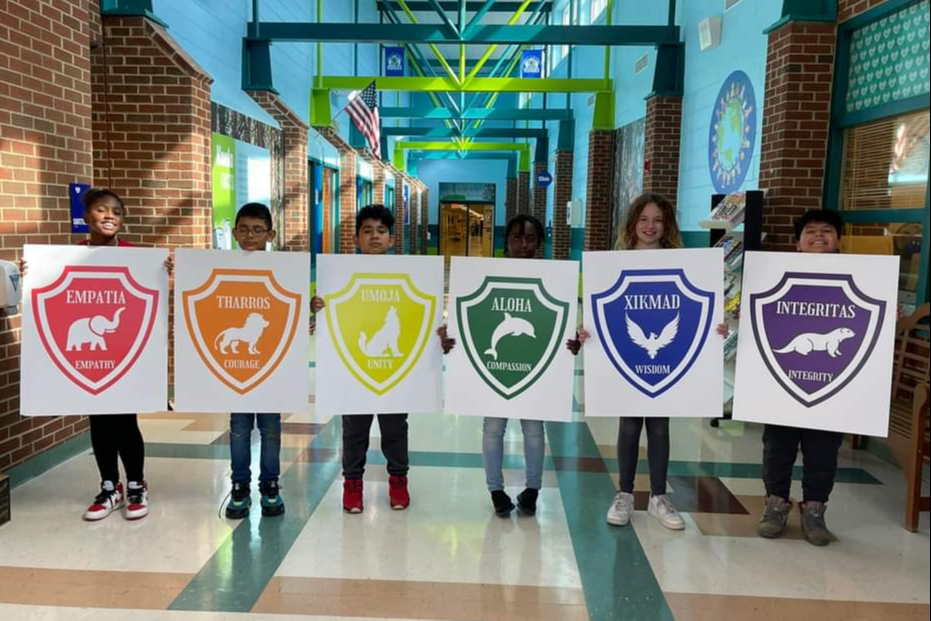 Students show off their house sign posters.