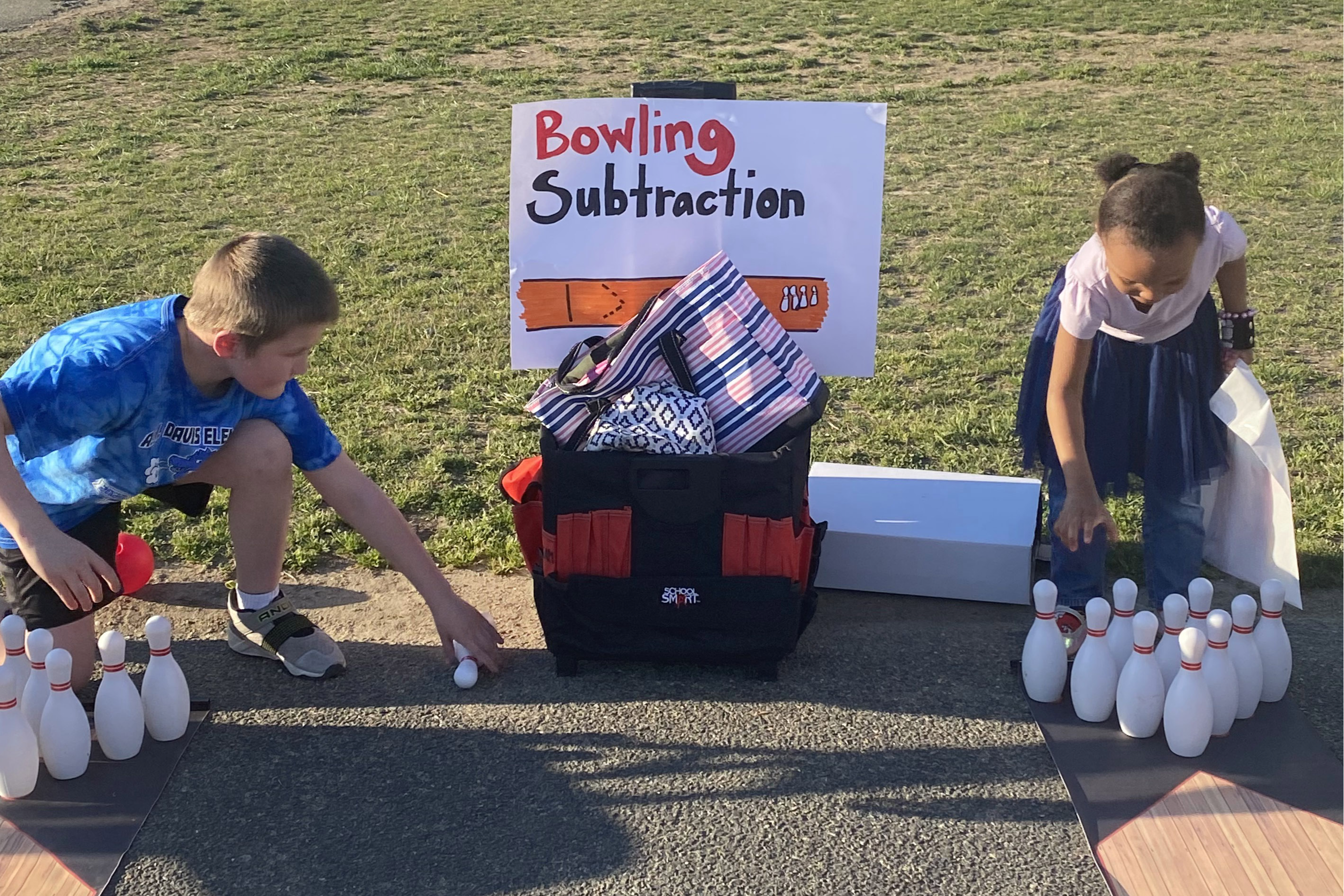 Two students playing bowling outside
