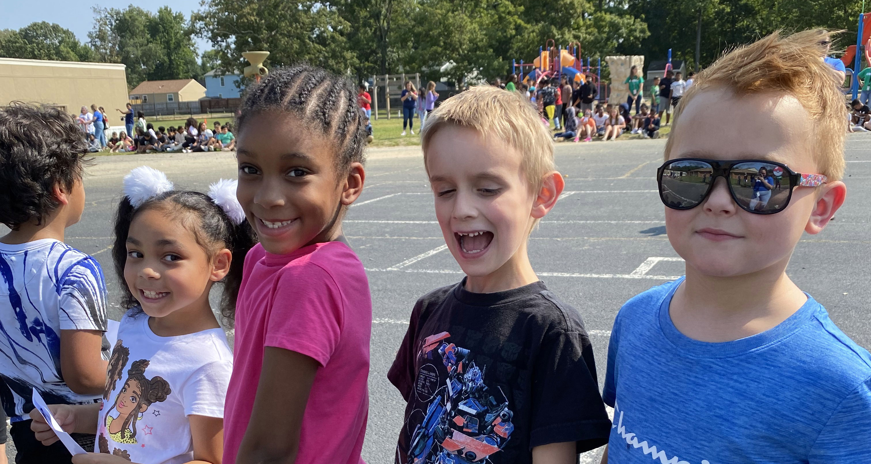 Four students smiling outside on the blacktop