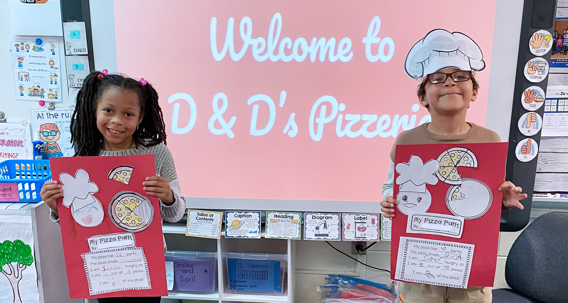 Two students holding up their pizza posters