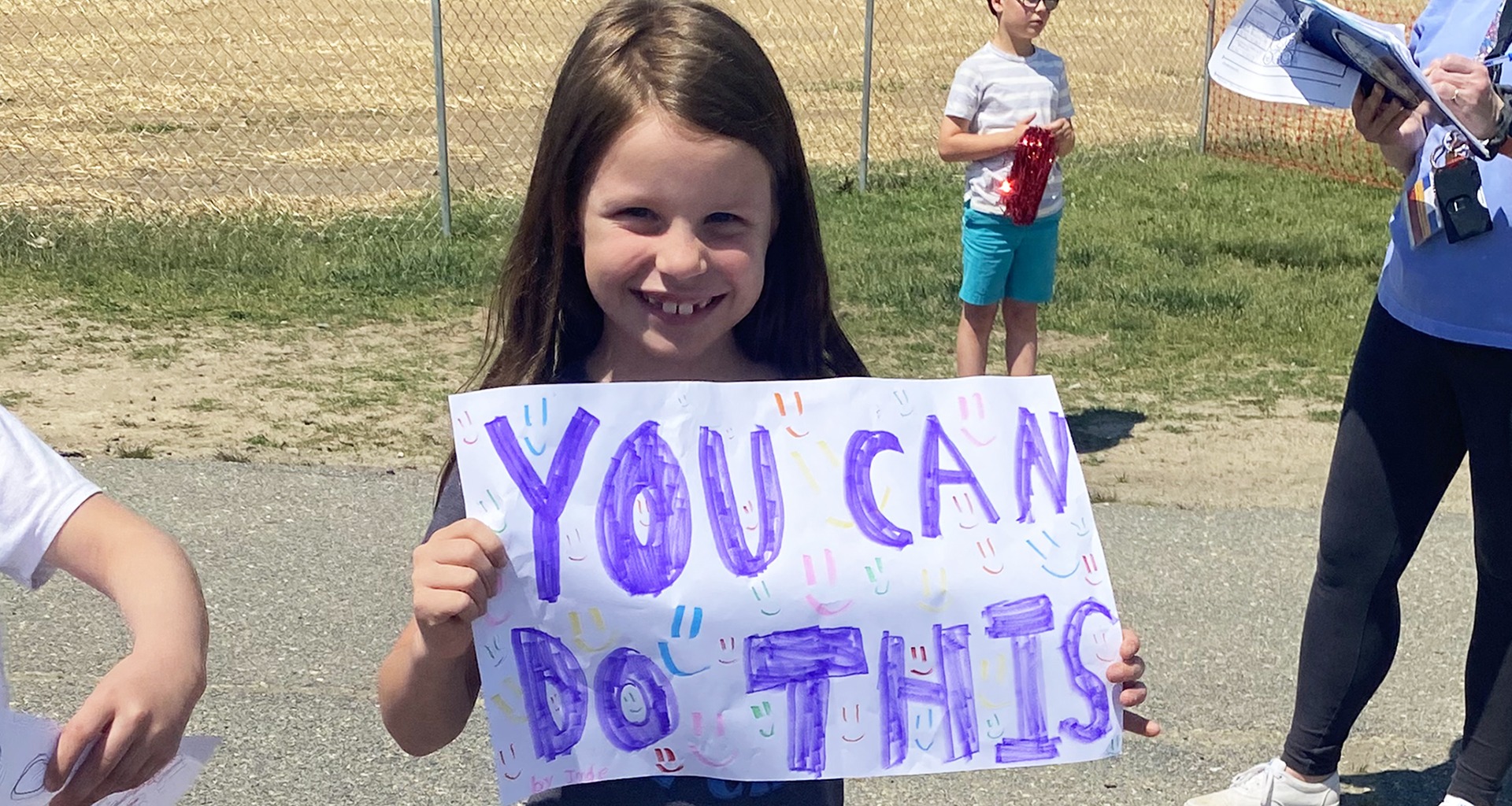 A student is holding up a you can do this sign