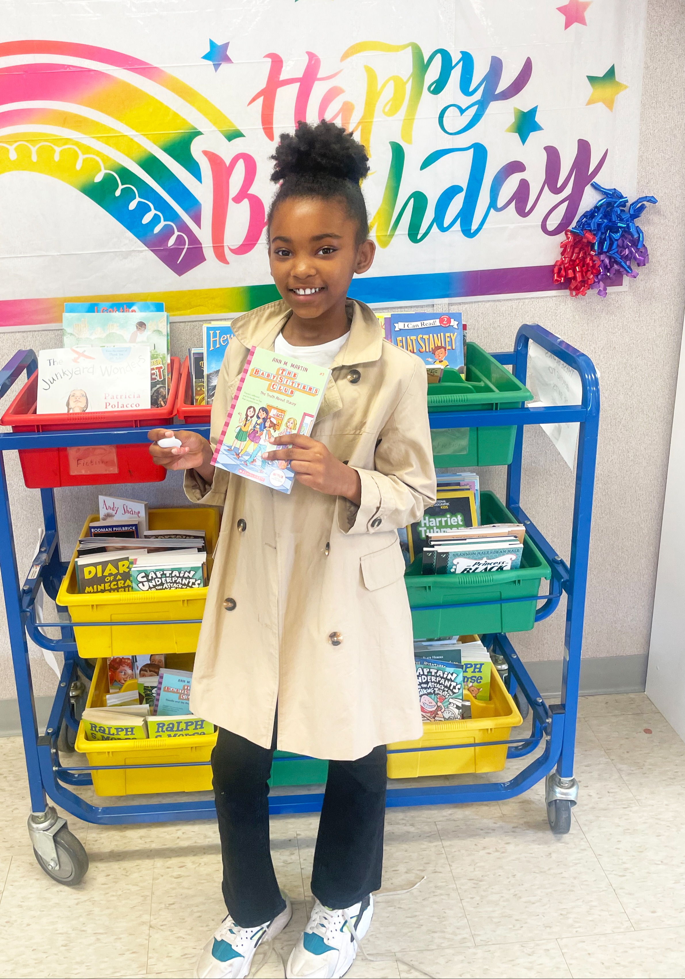A female student poses under happy birthday banner