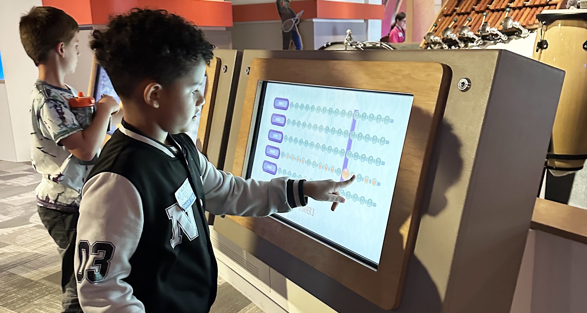 Two students playing with computers at museum