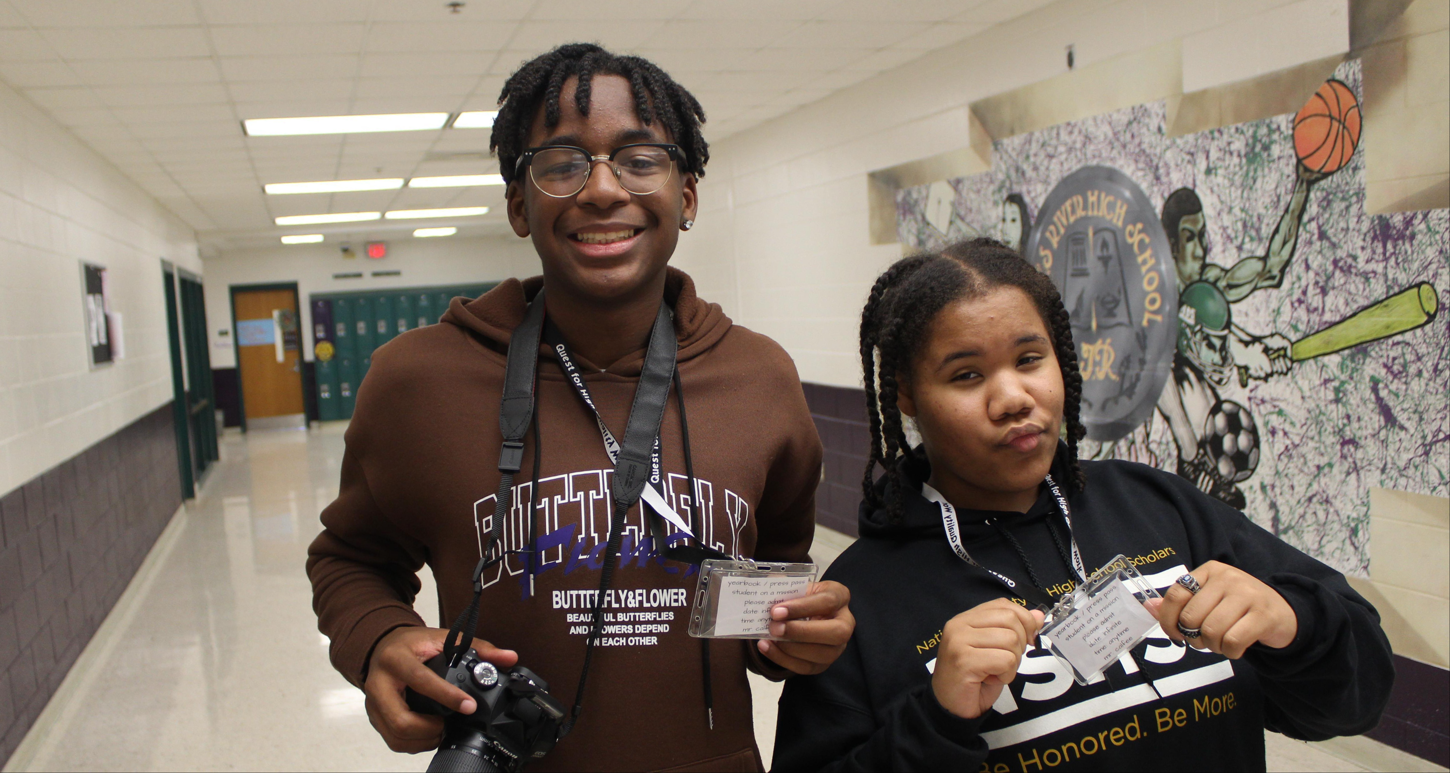 Two yearbook students holding their press pass in the hallway