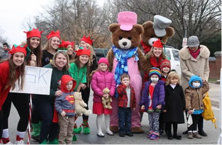 Students pose with young students outside.