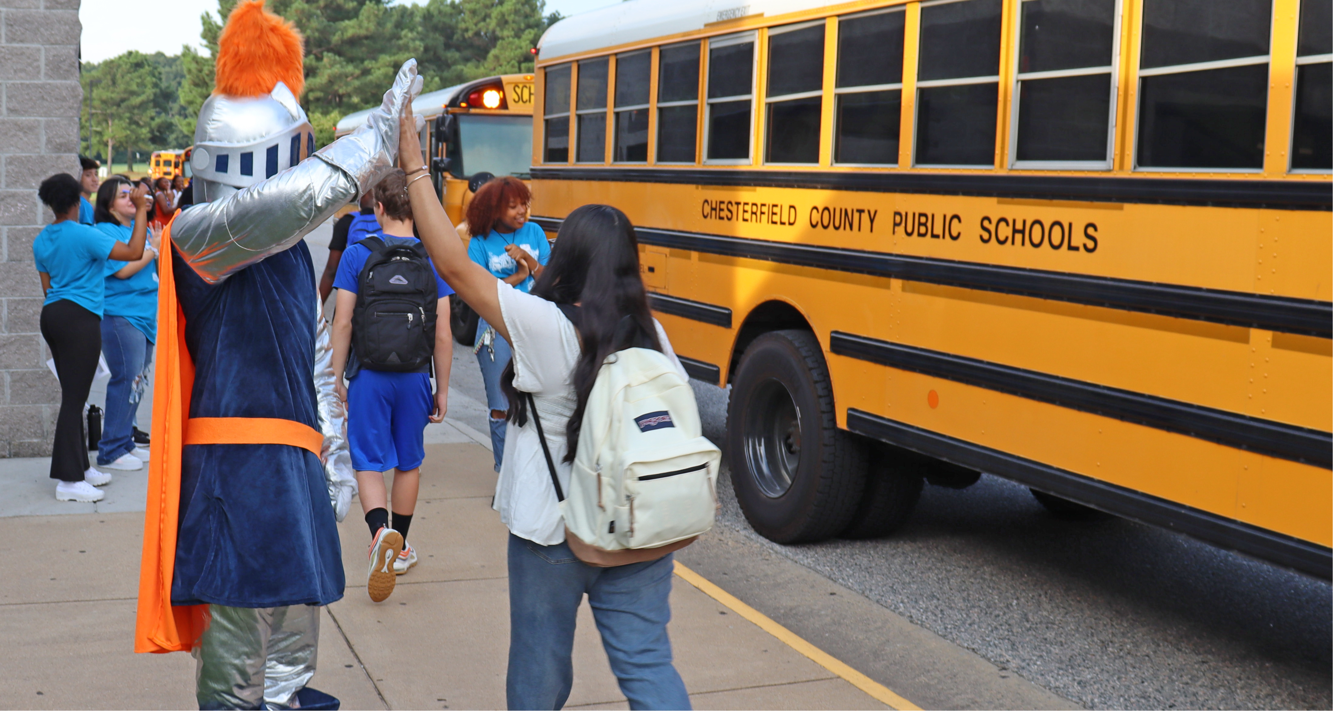 Lancer mascot high-fiving students as they get off the school bus