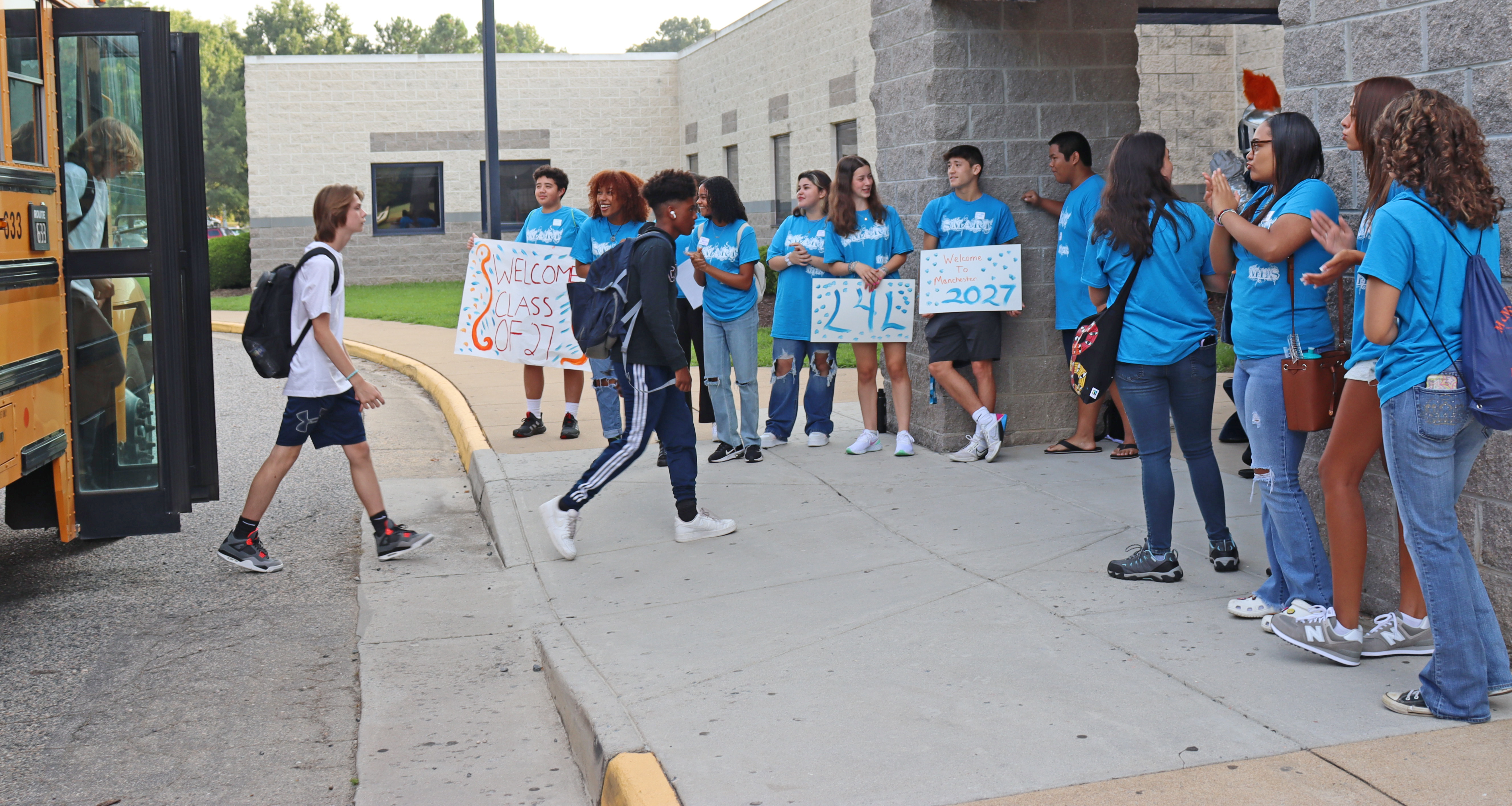 A group of students greeting other students as they enter school