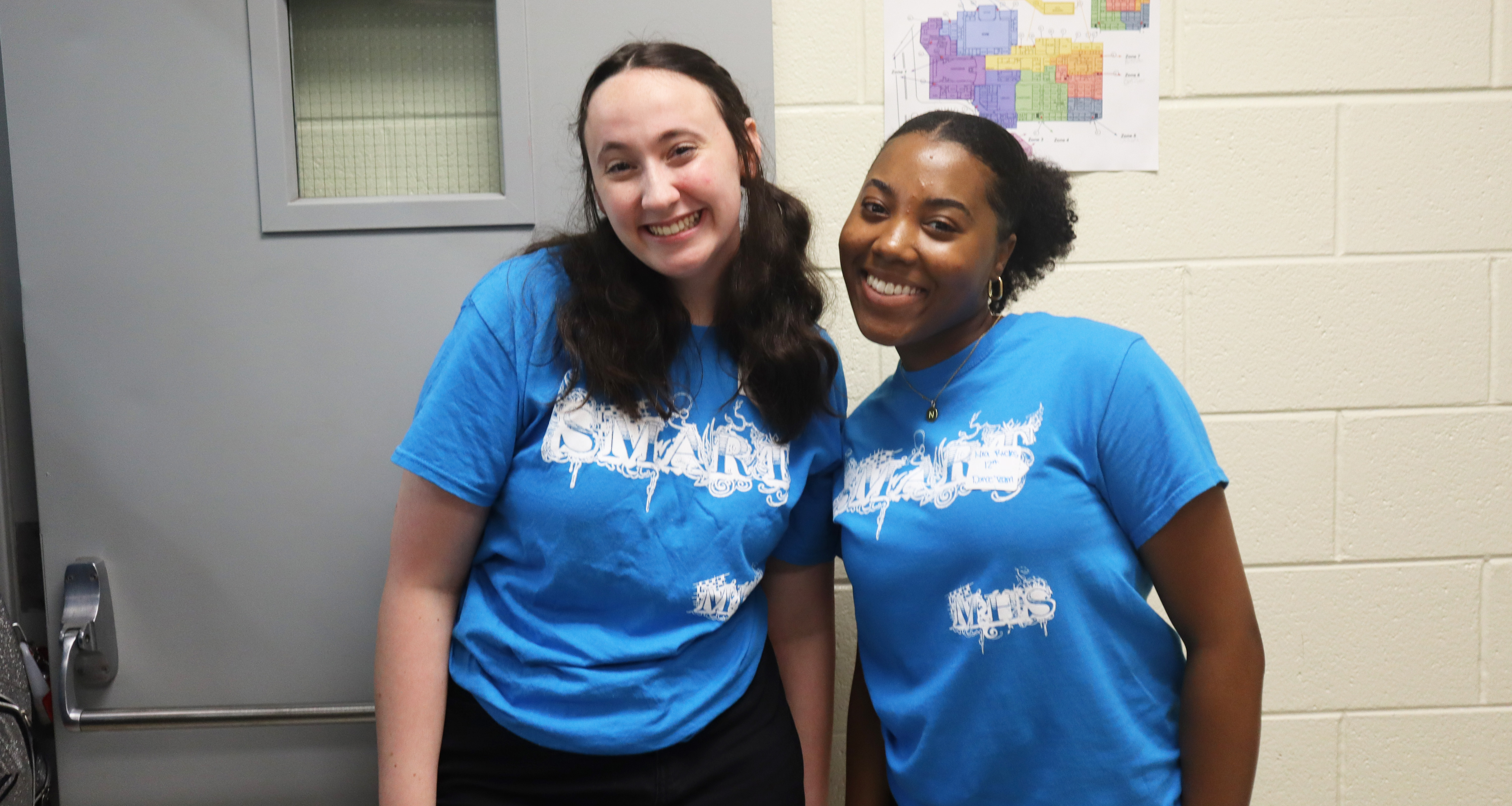 Two students wearing a blue shirt pose for a photo