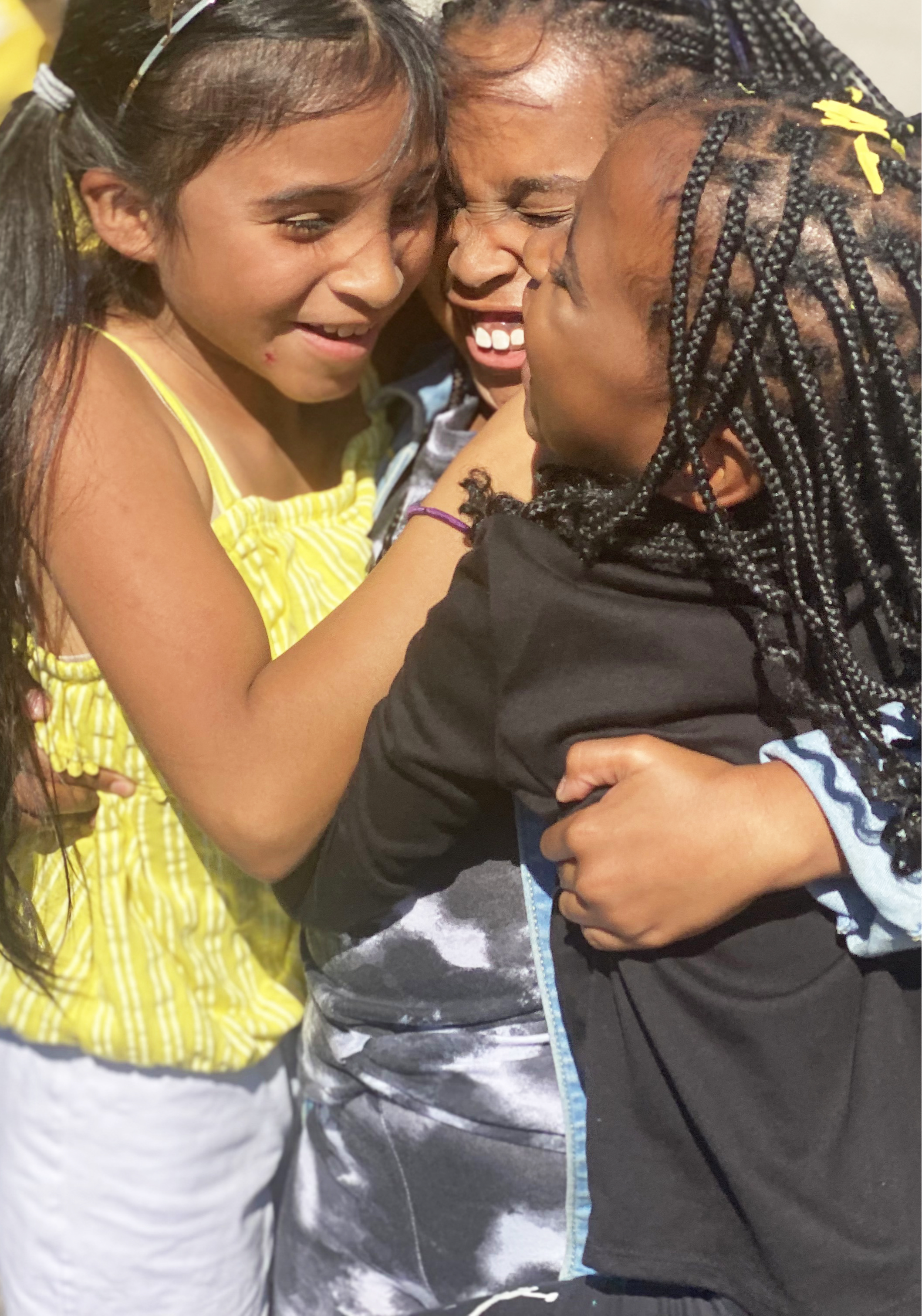 Three young females in a big group hug.