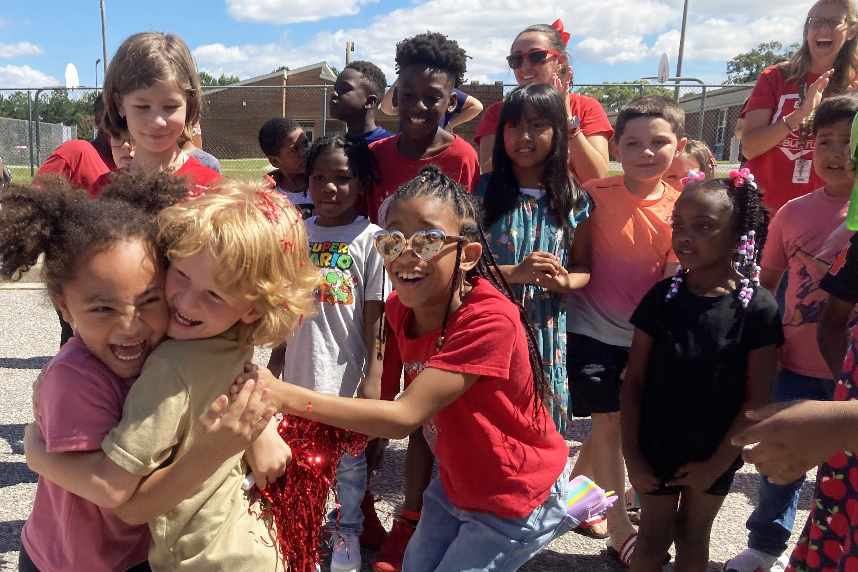 Large group of students outside. Two girls hugging.