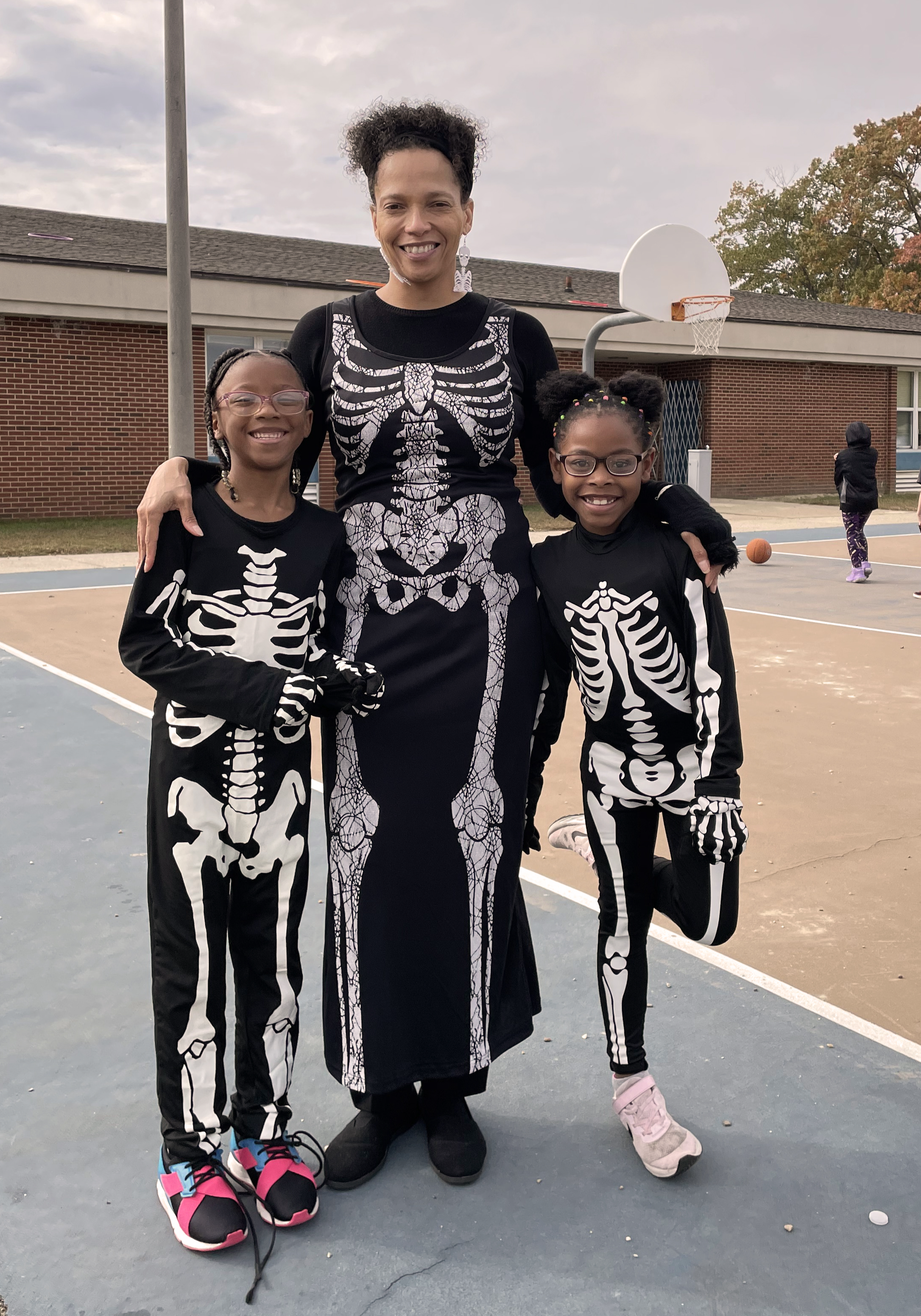 Teacher and two students dressed in skeleton costumes.