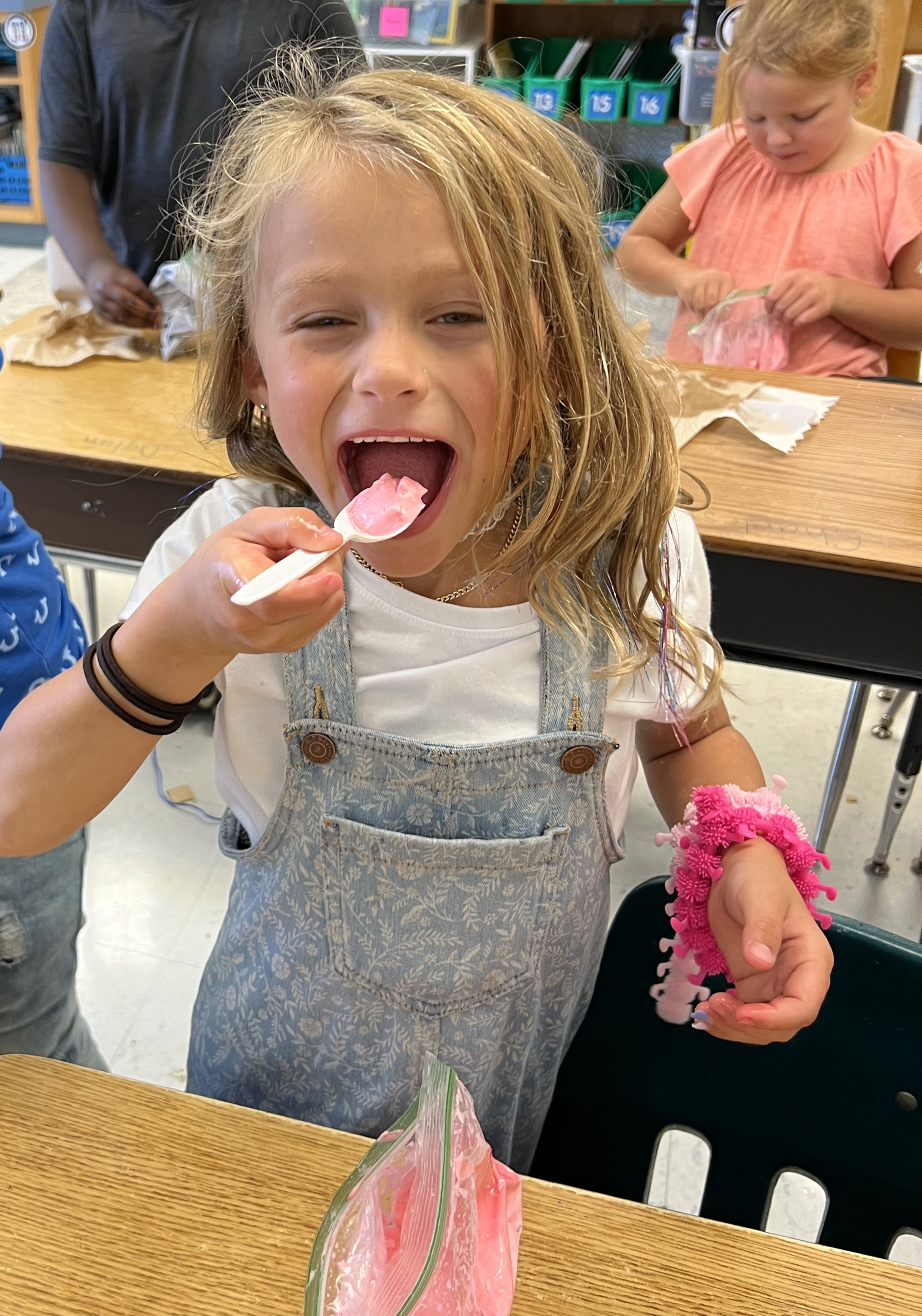 Young female taking a big bite of something pink.
