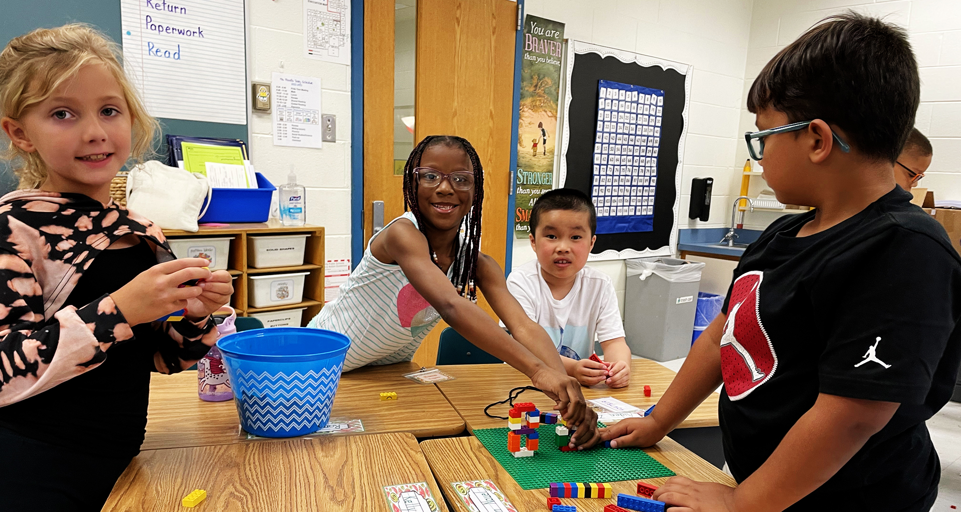 Four students working with blocks at a large table.
