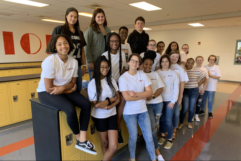 A large group of students pose for a photo in the locker room area