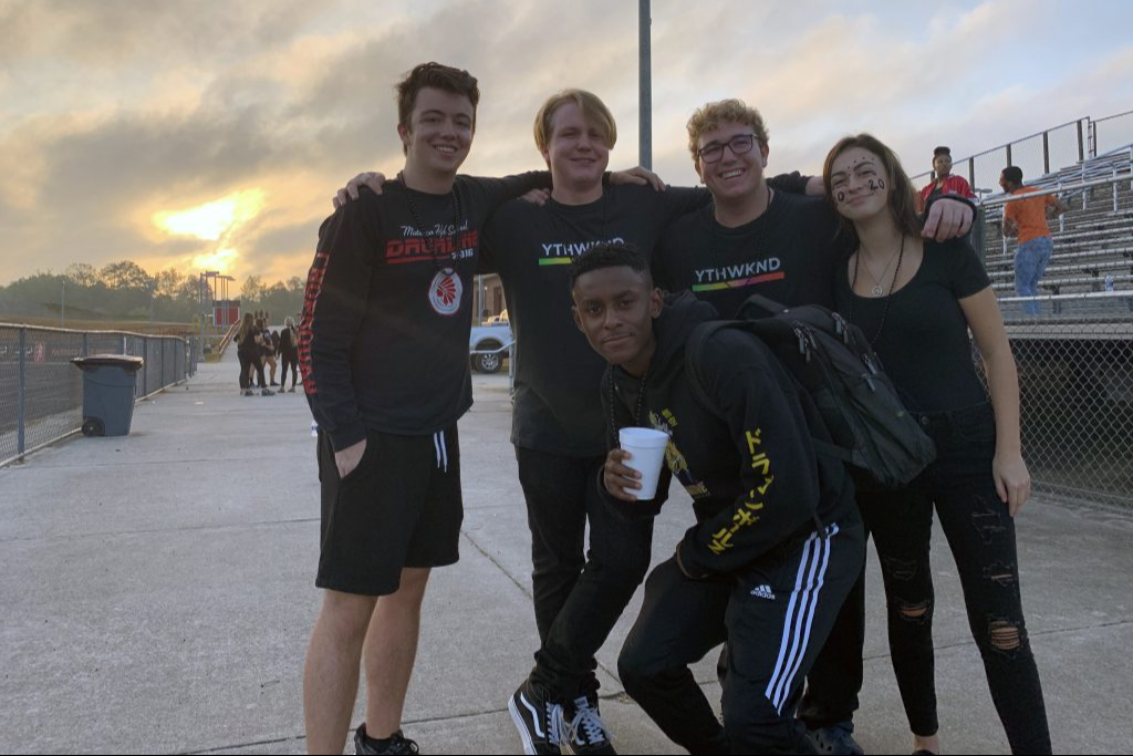 Five students pose for a photo near the school stadium