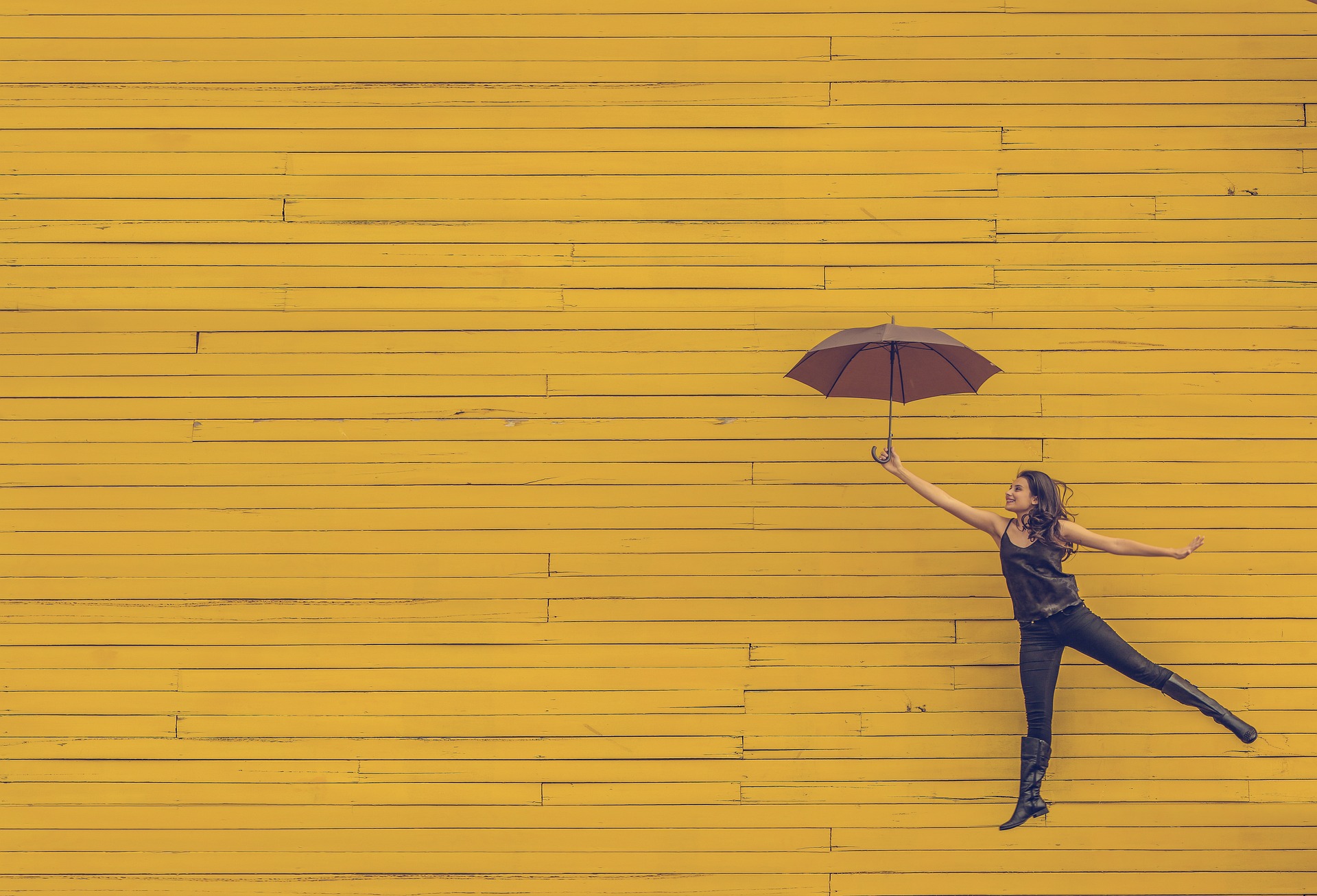 Woman with umbrella and yellow wall